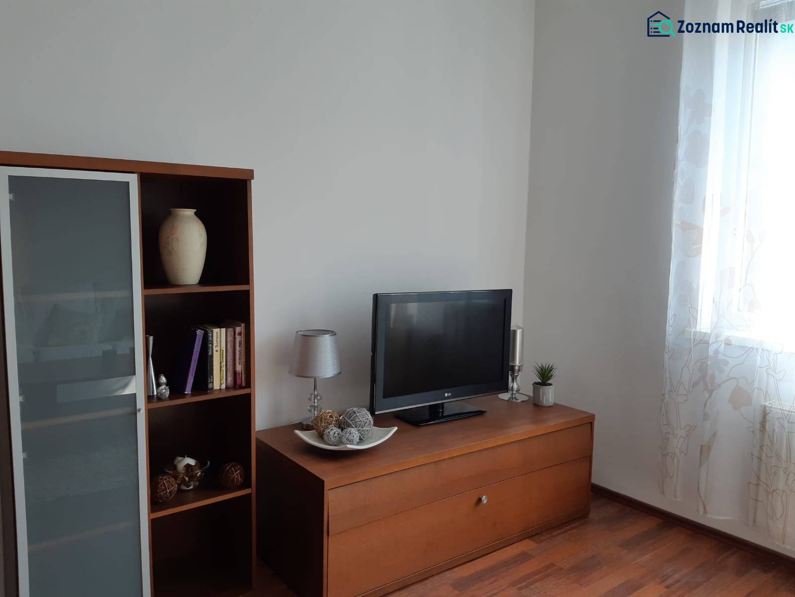 3 izb. byt v úplnom centre pri Šafárikovom námestí - Obývačka s podlahou s dreveným dekorom, knižnicou, televízorom a dekoratívnymi predmetmi.