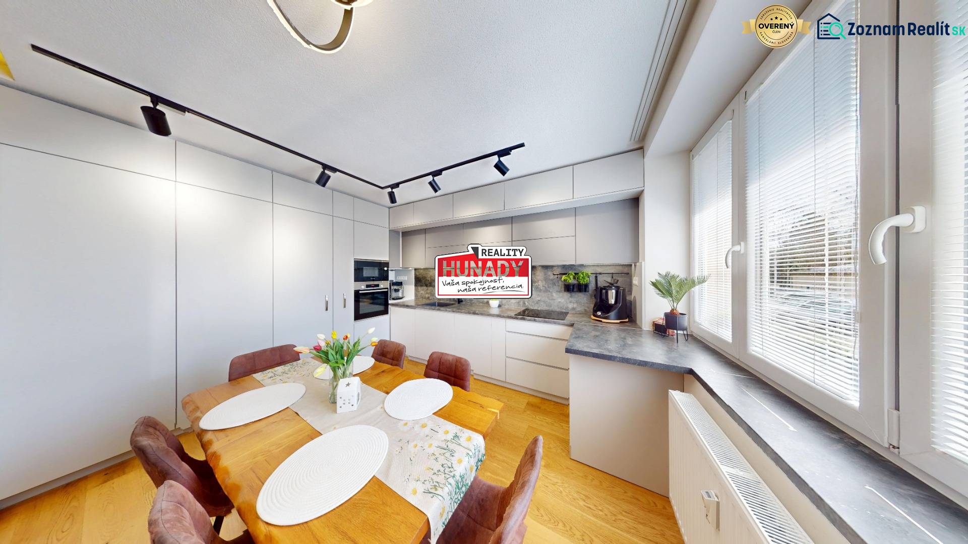 (81 m²) ŠTÝLOVÝ 3i BYT NA SEVERE - Kuchyňa v 3-izbovom byte s podlahou s dreveným dekorom a veľkým jedálenským stolom.