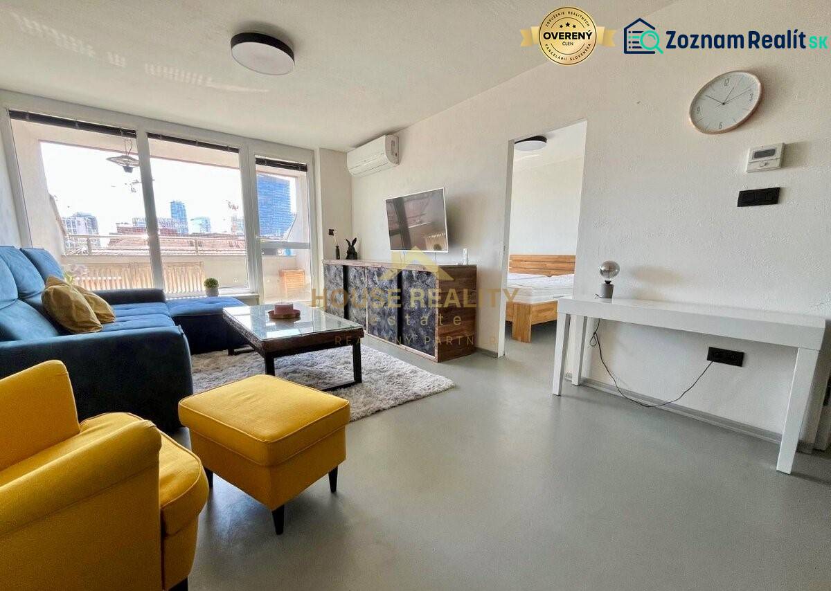 Nadstavba krásny 2,5 izb. byt, Dulovo námestie, Bratislava II. Ružinov - Obývacia izba 3-izbového bytu so sedačkou, televízorom a balkónom.
