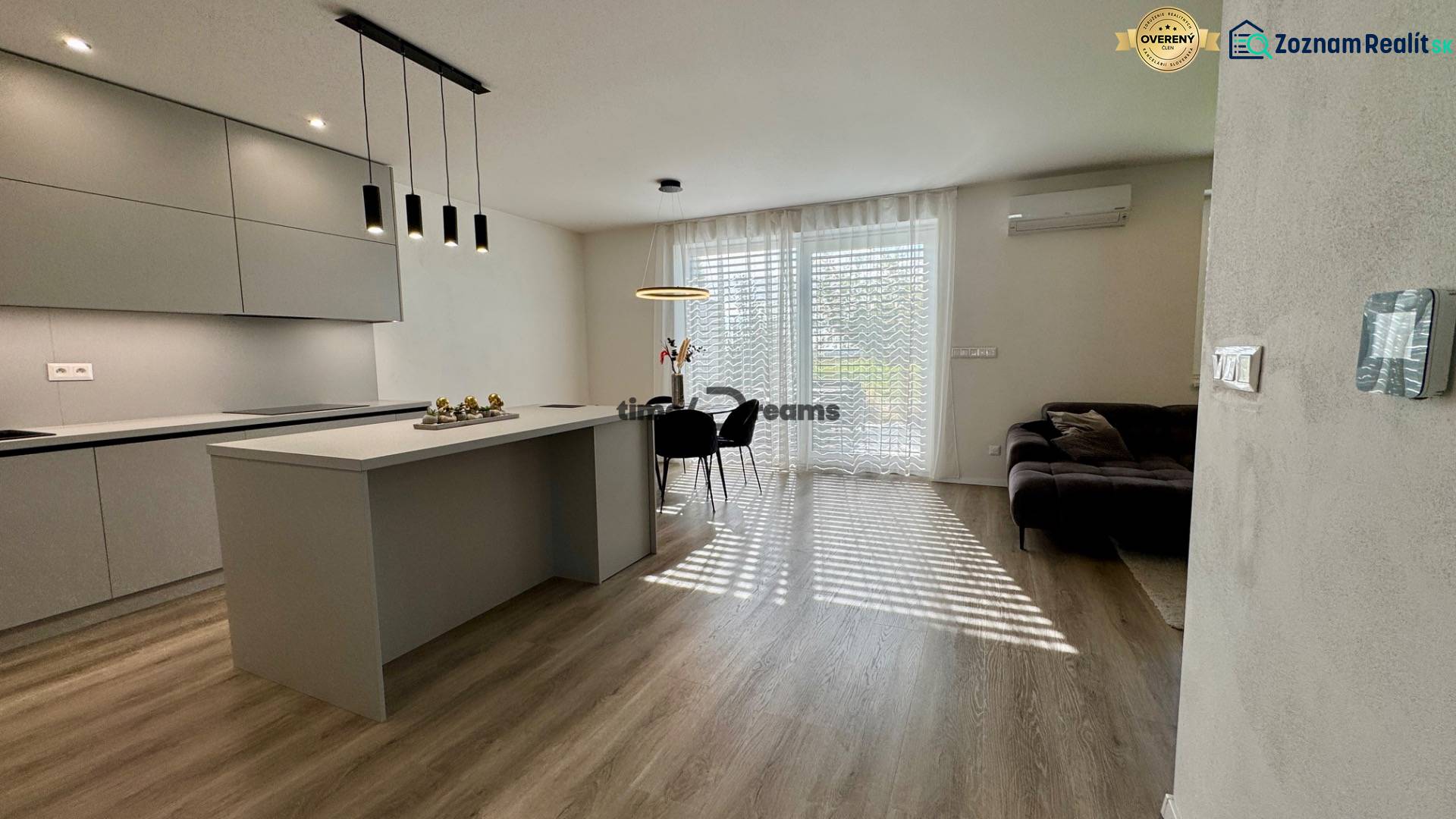 NA PREDAJ 4 izbový rodinný dom Štitáre NITRA - Kuchyňa v rodinnom dome s ostrovčekom, veľkými oknami a podlahou s dreveným dekorom.