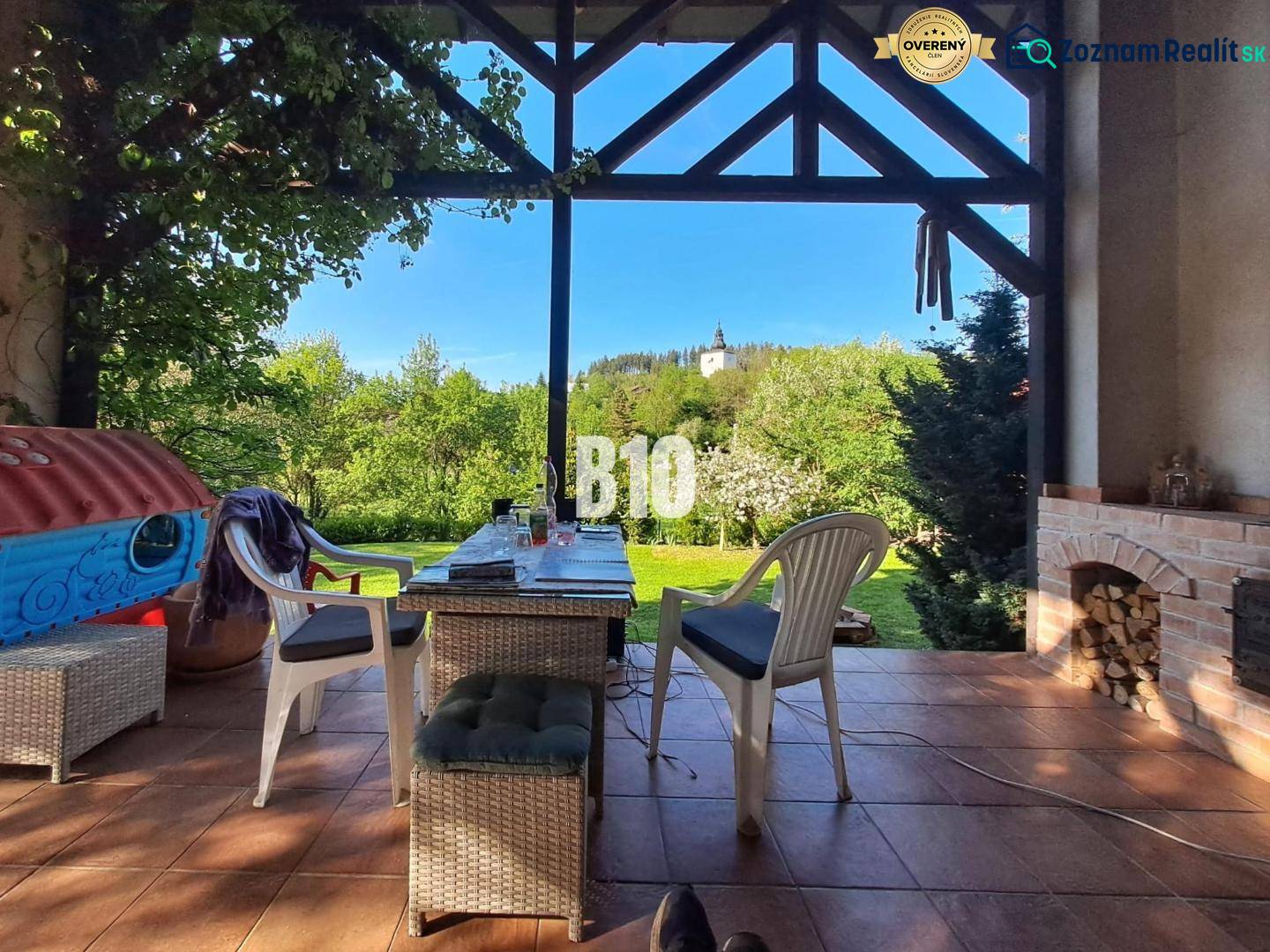 Zaujímavý rodinný dom s veľkým pozemkom, krásnou záhradou a bohatým pr - Terasa rodinného domu v Lietave s výhľadom na kostol, stôl a stoličky.