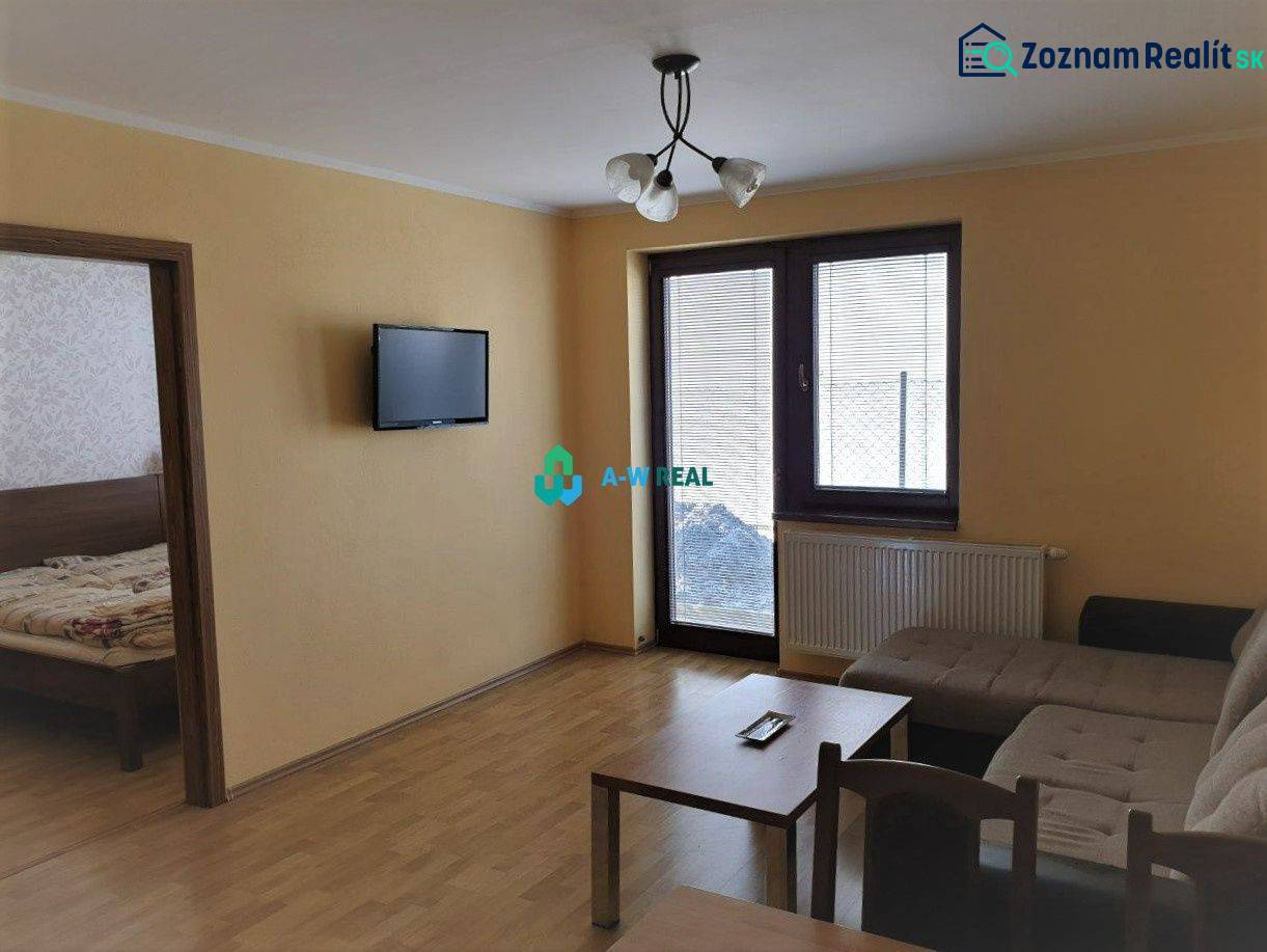 Apartmánový dom na predaj blízko termálneho kúpaliska - Obývacia izba s pohovkou, televízorom na stene a dreveným nábytkom, na ulici neuvedené.