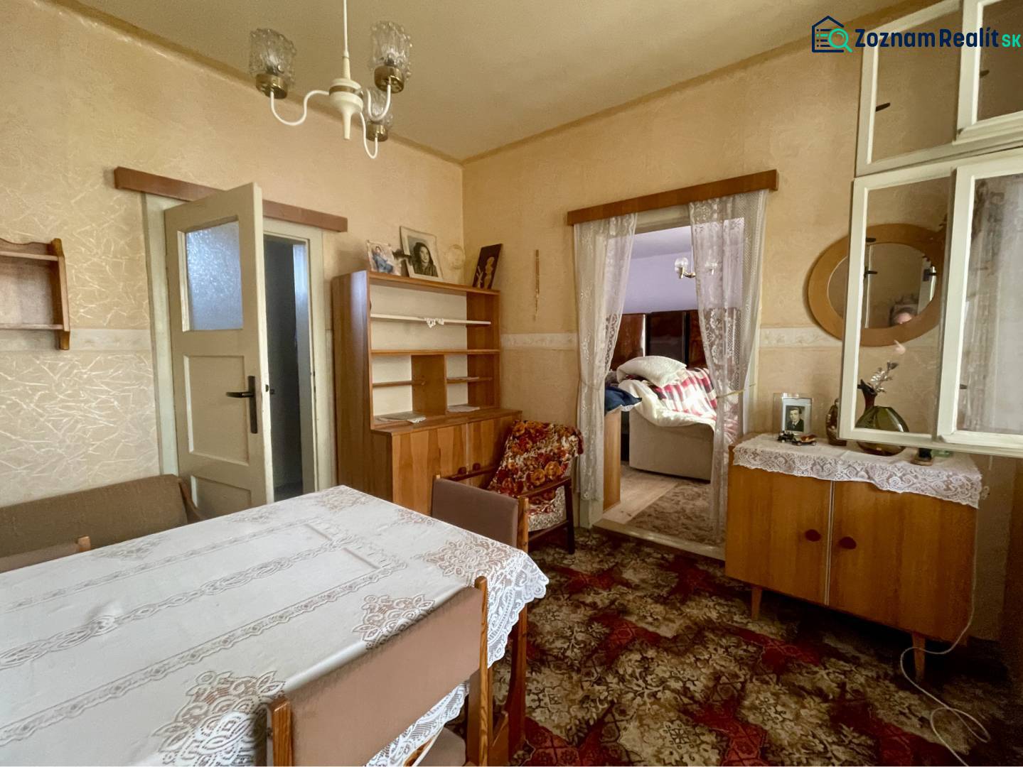 VRAKÚŇ – STARÝ RODINNÝ DOM NA PREDAJ S VEĽKÝM POZEMKOM - 24 ÁROV - Tradičná jedáleň v rodinnom dome s čipkovaným obrusom a dreveným nábytkom.