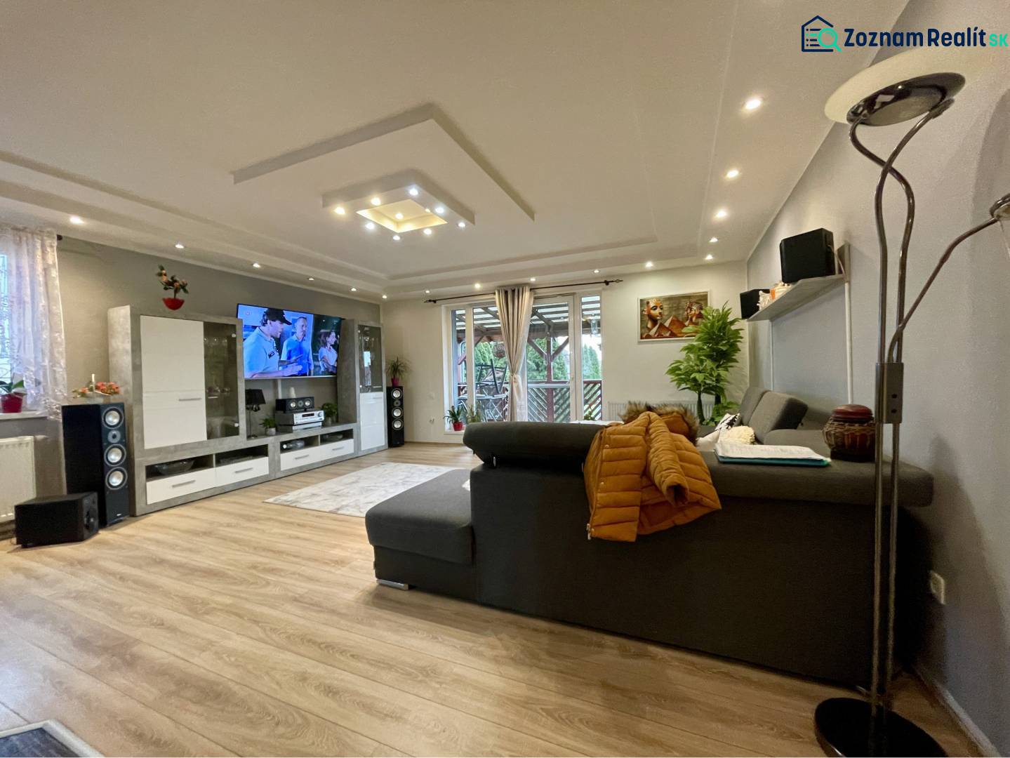 VKUSNÝ 4-IZBOVÝ RODINNÝ DOM S GARÁŽOU NA PREDAJ V OBCI TOPOĽNÍKY - Obývačka v rodinnom dome s podlahou s dreveným dekorom a veľkým sedením.