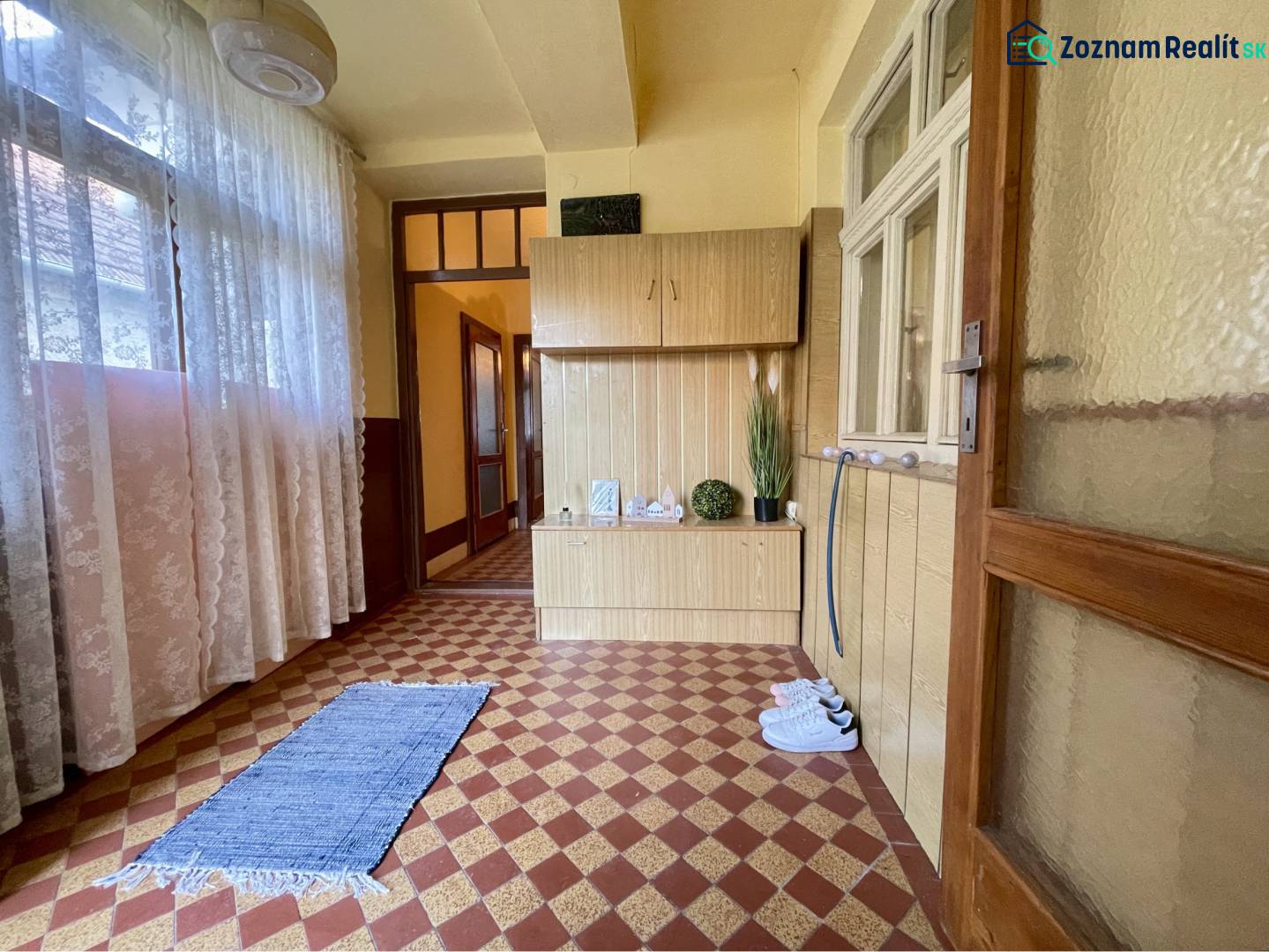 TOPOĽNÍKY – 4-IZBOVÝ RODINNÝ DOM NA PREDAJ NA 14 ÁROVOM POZEMKU - Vnútorný priestor rodinného domu, koberček, závesy, drevený nábytok, kvetinová dekorácia.