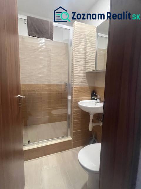 Apartmány na prenájom. - Malá kúpeľňa so sprchovým kútom, umývadlom a toaletou, obkladačky a drevené dvere.