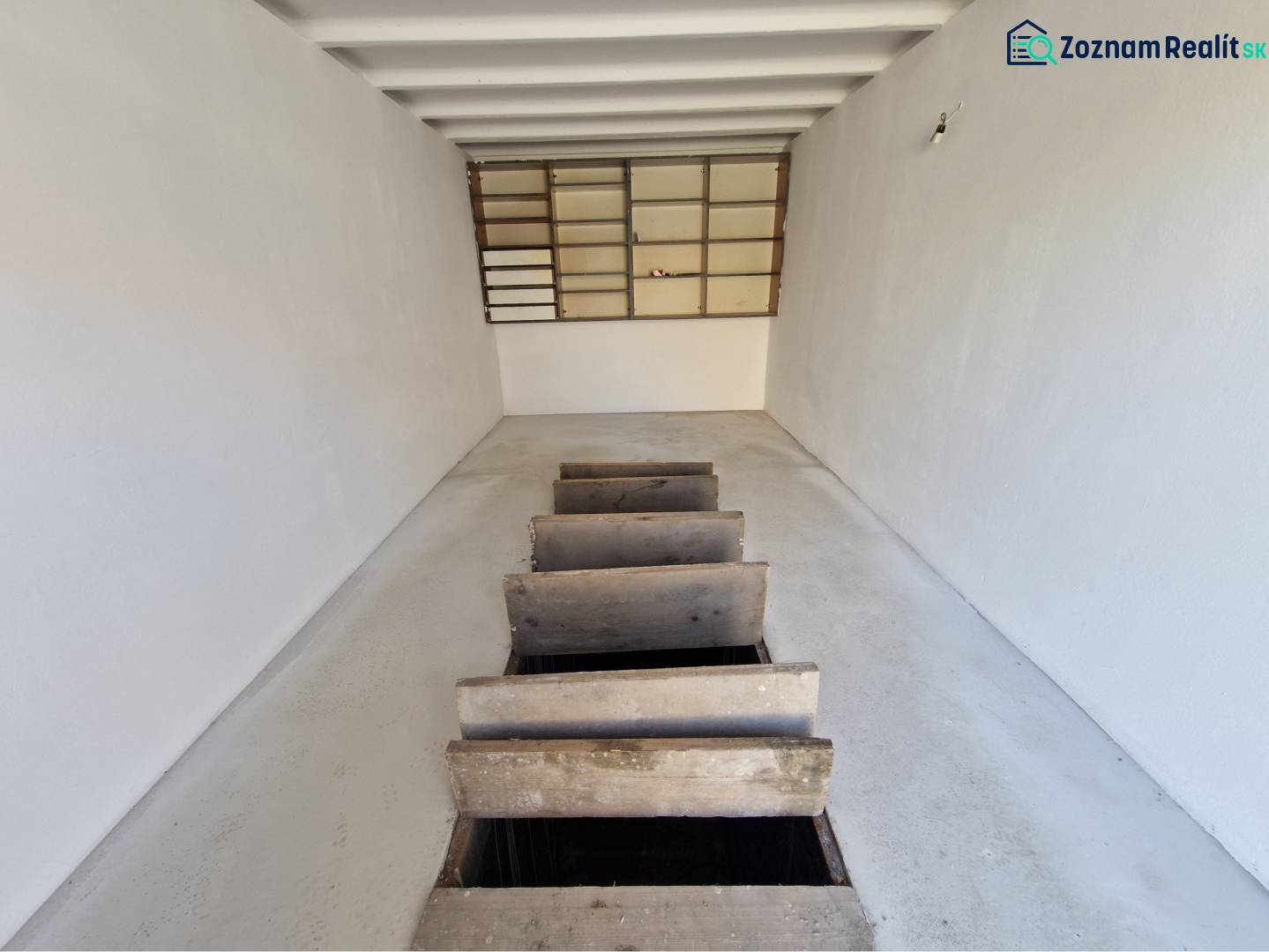 REZERVOVANÉ! Murovaná garáž - Garáže s bielymi stenami a dreveným poklopom na podlahe.