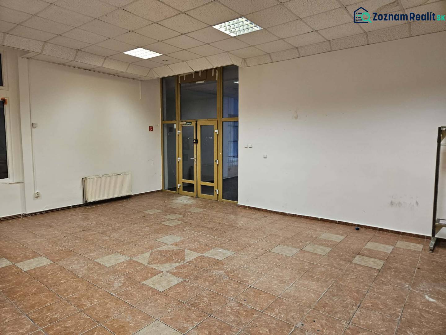 Exkluzívny obchodný priestor na prenájom v centre Dunajskej Stredy – u - Prázdne obchodné priestory s keramickou podlahou a presklenými dverami.