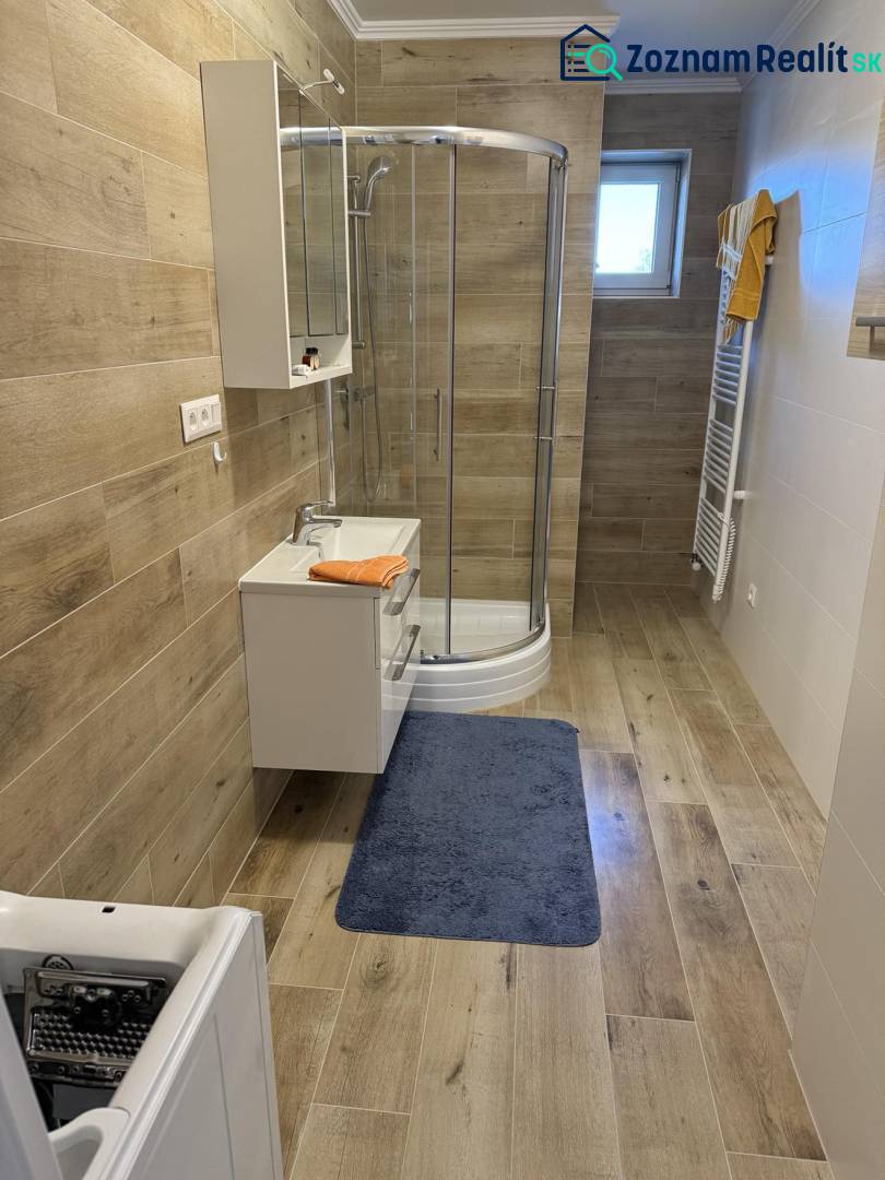 Prenájom 2-izbového bytu, Dunajská Streda - Kúpeľňa v 2-izbovom byte s podlahou s dreveným dekorom a sprchovacím kútom.