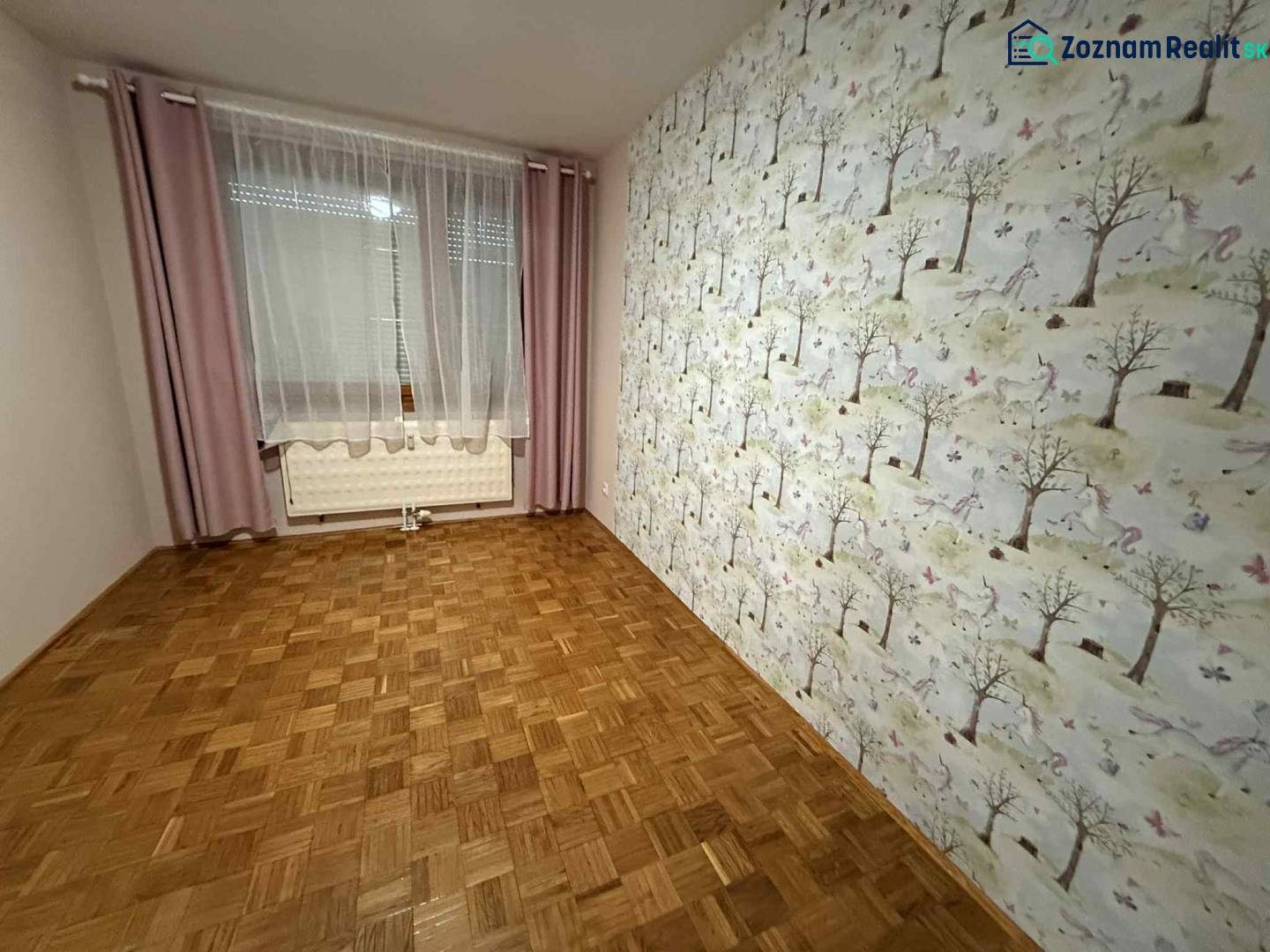 Prenájom 3-izbového bytu, Dunajská Streda - Izba v 3-izbovom byte s tapetou s lesným motívom a podlahou s dreveným dekorom.