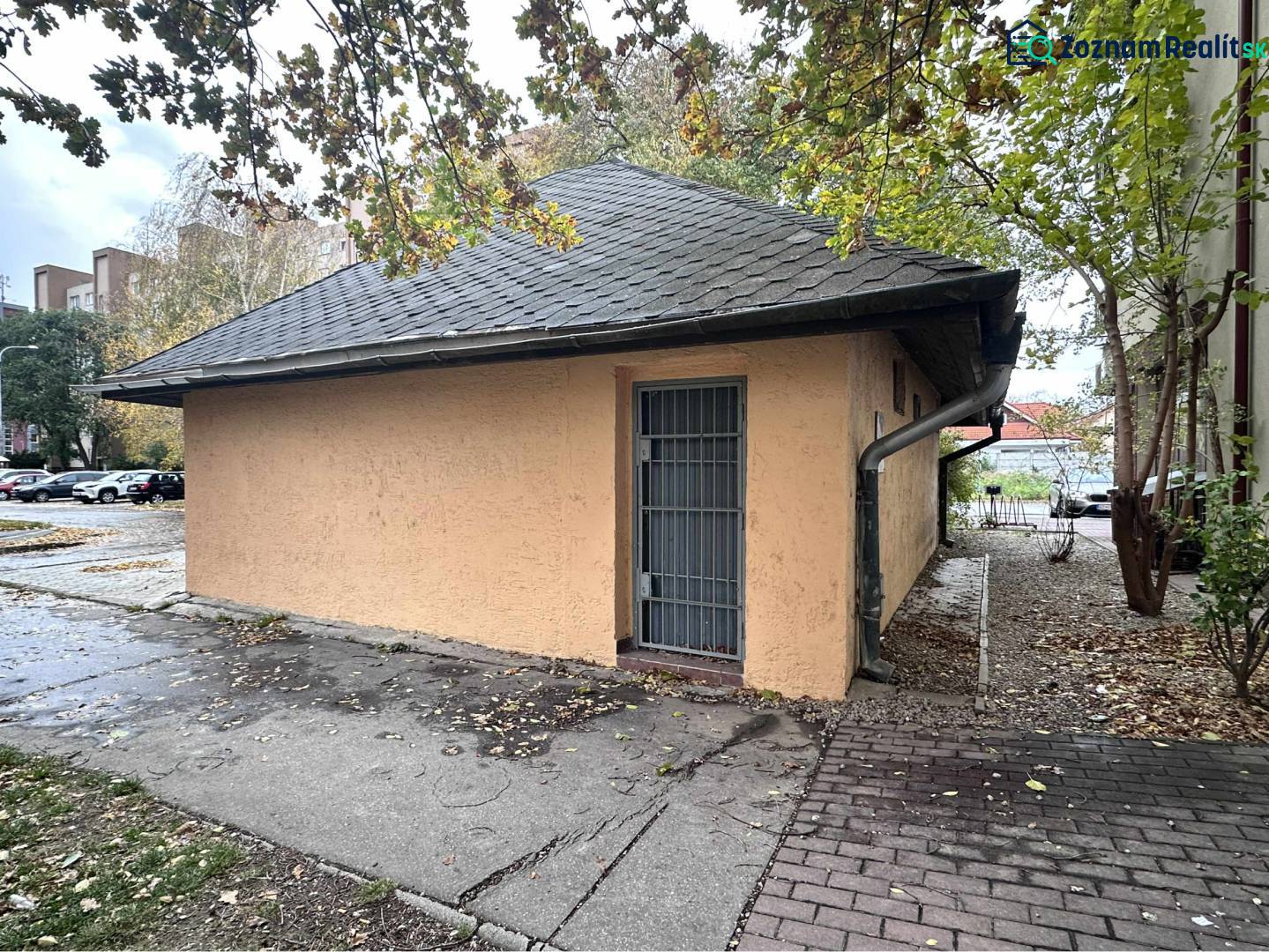 ☎️ 0918197701- Znížená cena     Predaj – Obchodný priestor v Dunajskej - Budova s plechovými dverami obklopená stromami a zaparkovanými autami v Dunajskej Strede.
