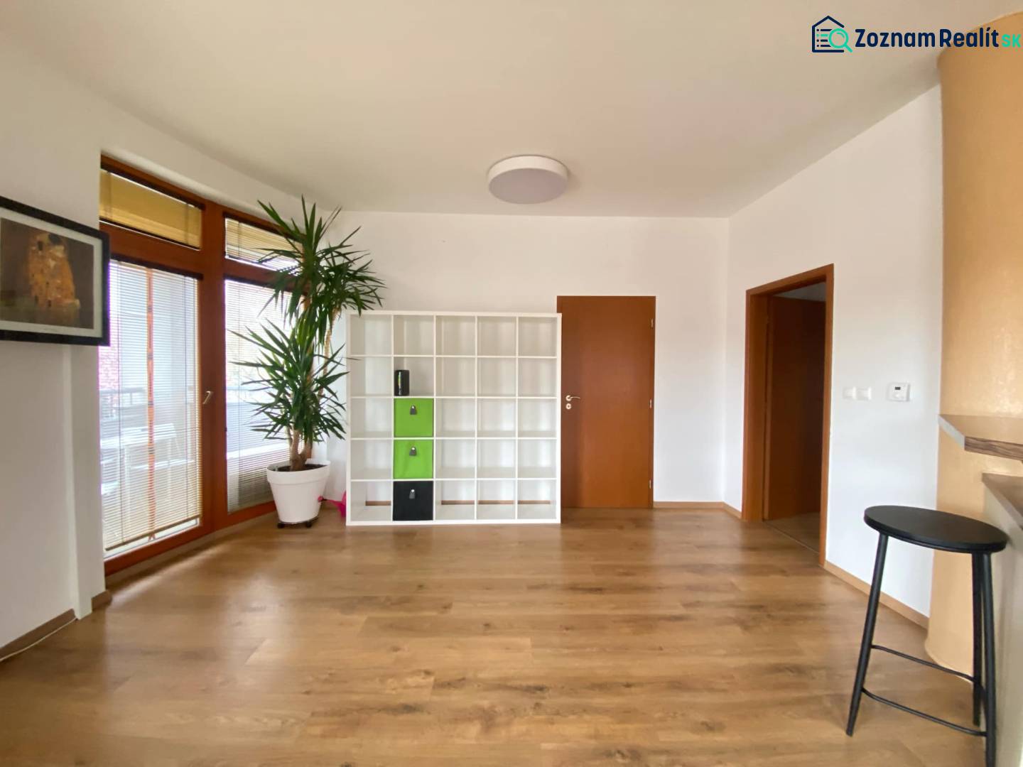 ☎️ 0918197701   Na predaj  elegantný 3 izbový byt priamo v centre Duna - Obývacia izba v 3-izbovom byte s podlahou s dreveným dekorom a bielou policovou skriňou.