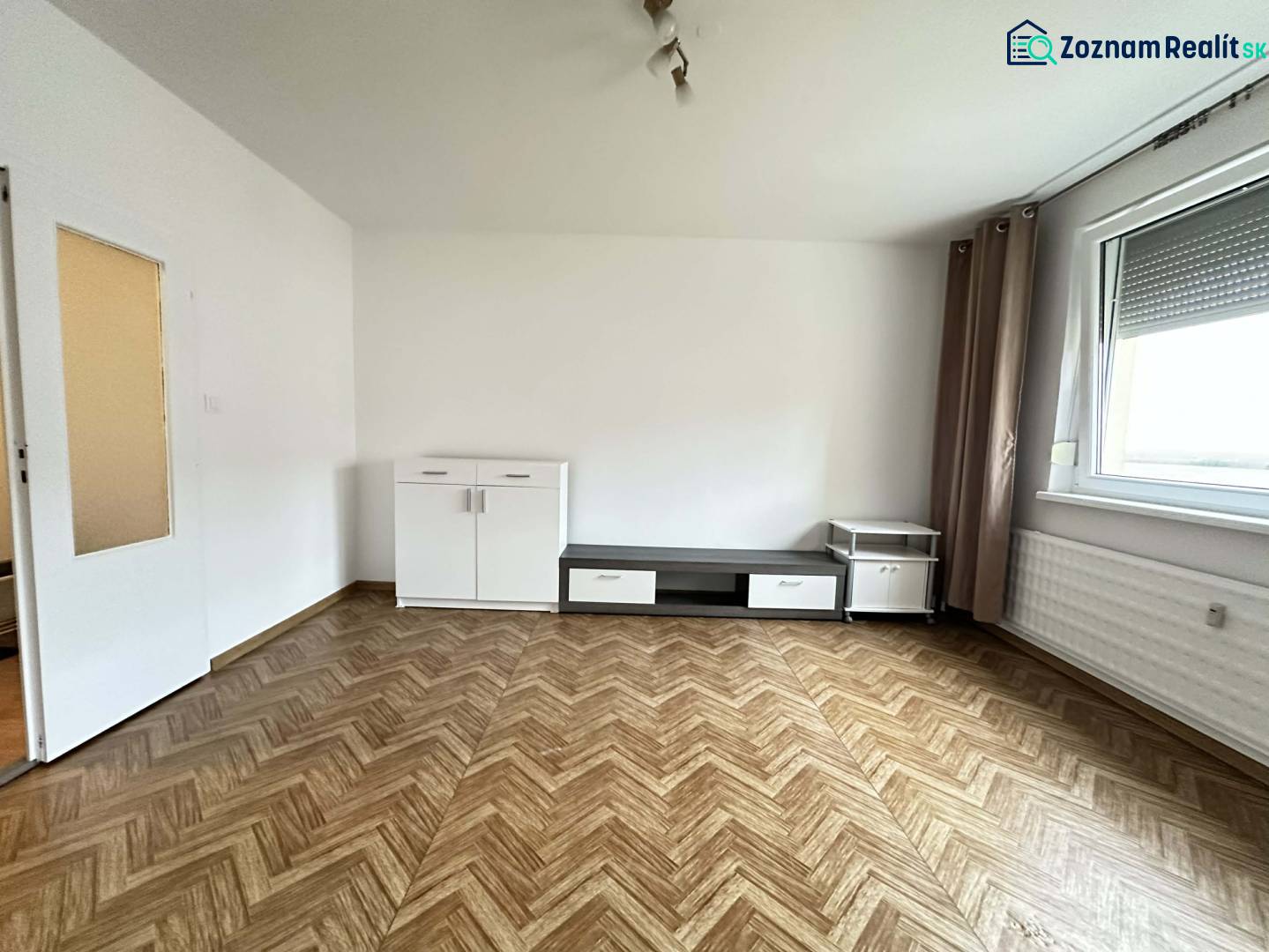 ☎️  0918/197 701  Na prenájom 1 izbový byt s balkónom a pivnicou v mes - Izba s podlahou s dreveným dekorom, bielym nábytkom a veľkým oknom v 1-izbovom byte.