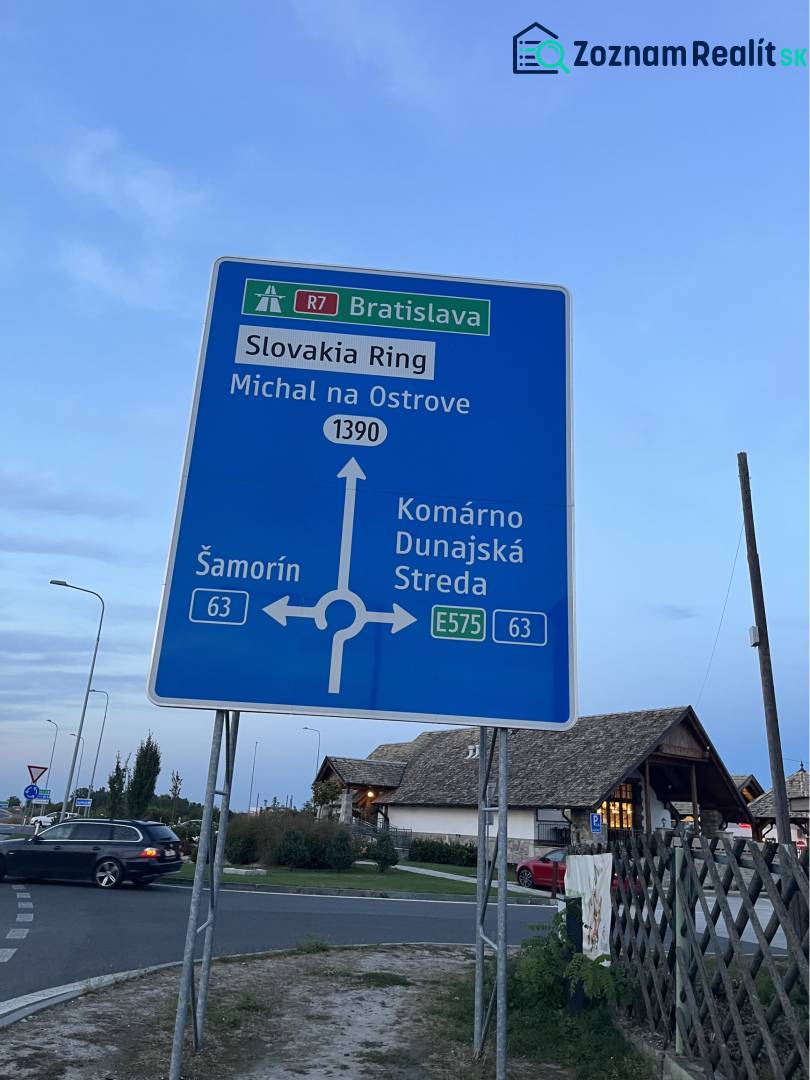 ZNÍŽENÁ CENA! Stavebný pozemok o rozlohe 557 m2 v Holiciach! - Dopravná značka smerujúca na rôzne destinácie vrátane Slovakia Ringu a Bratislavy.