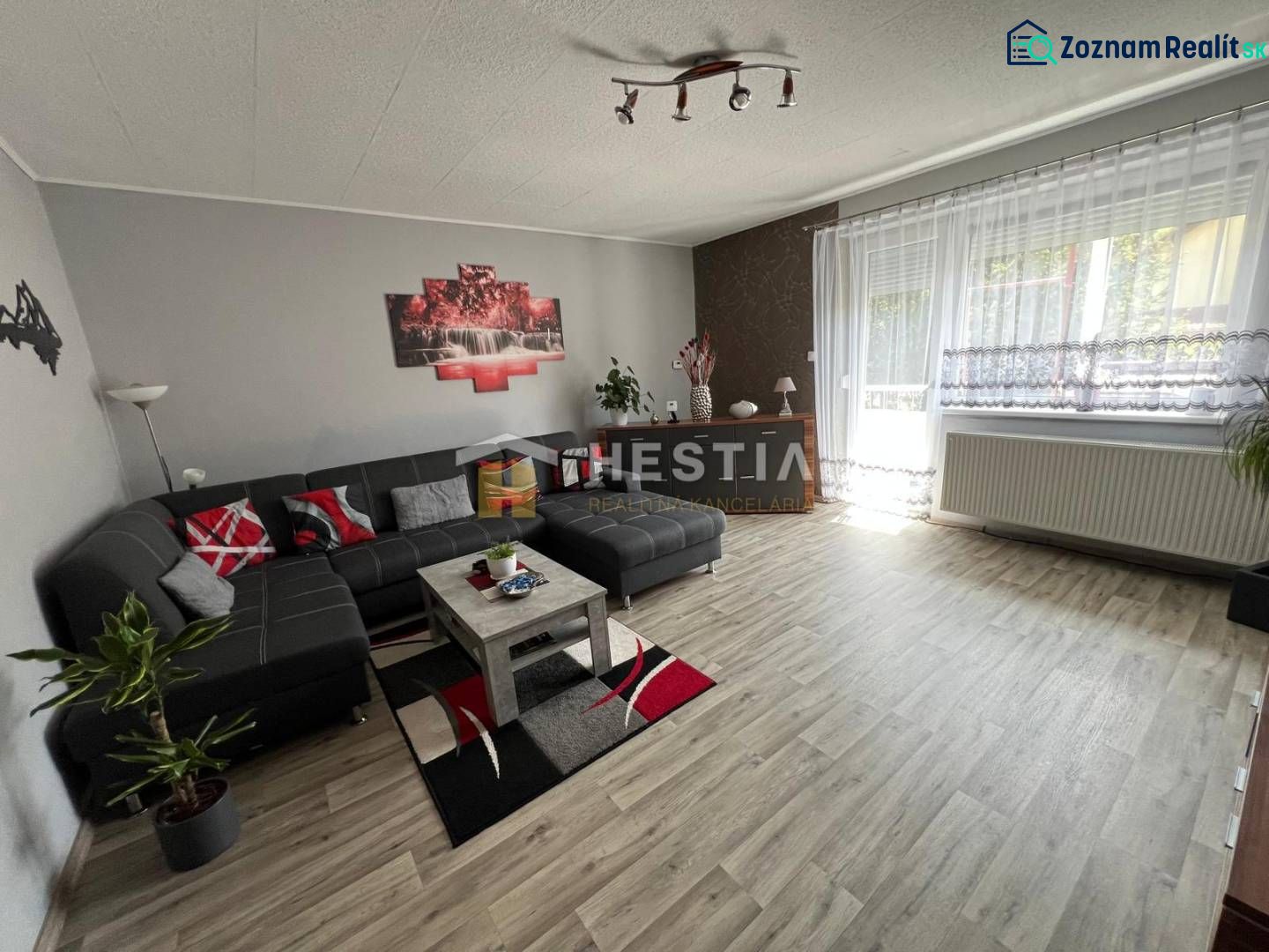 NOVINKA Priestranný 3-izbový byt (99 m²) s pozemkom, terasou, 2 balkón - Priestranná obývačka v 3-izbovom byte s podlahou s dreveným dekorom a pohodlnou sedacou súpravou.