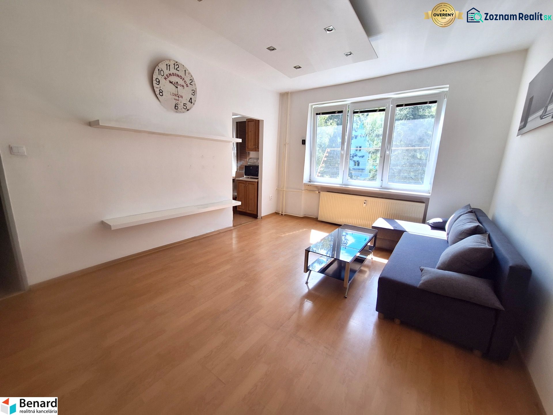 NA PRENÁJOM 1 IZBOVÝ TEHLOVÝ BYT, 34 M2, KOŠICE - ŠACA - Svetlá obývačka s podlahou s dreveným dekorom a sedačkou v 1-izbovom byte.