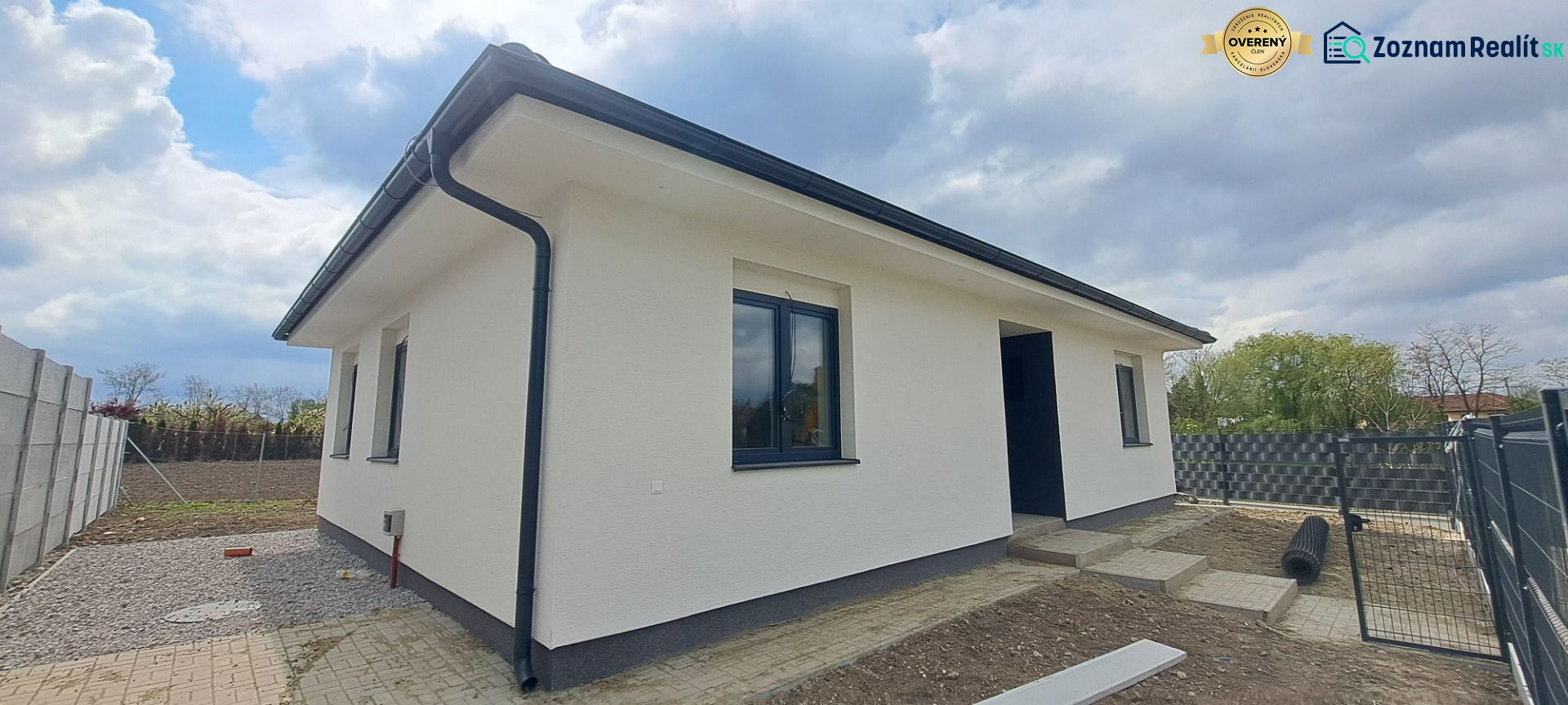 Novostavba pri jazere - 4 izbový rodinný dom v štandarde v obci Selice - Rodinný dom v Seliciach s bielou fasádou a čiernymi strešnými prvkami.