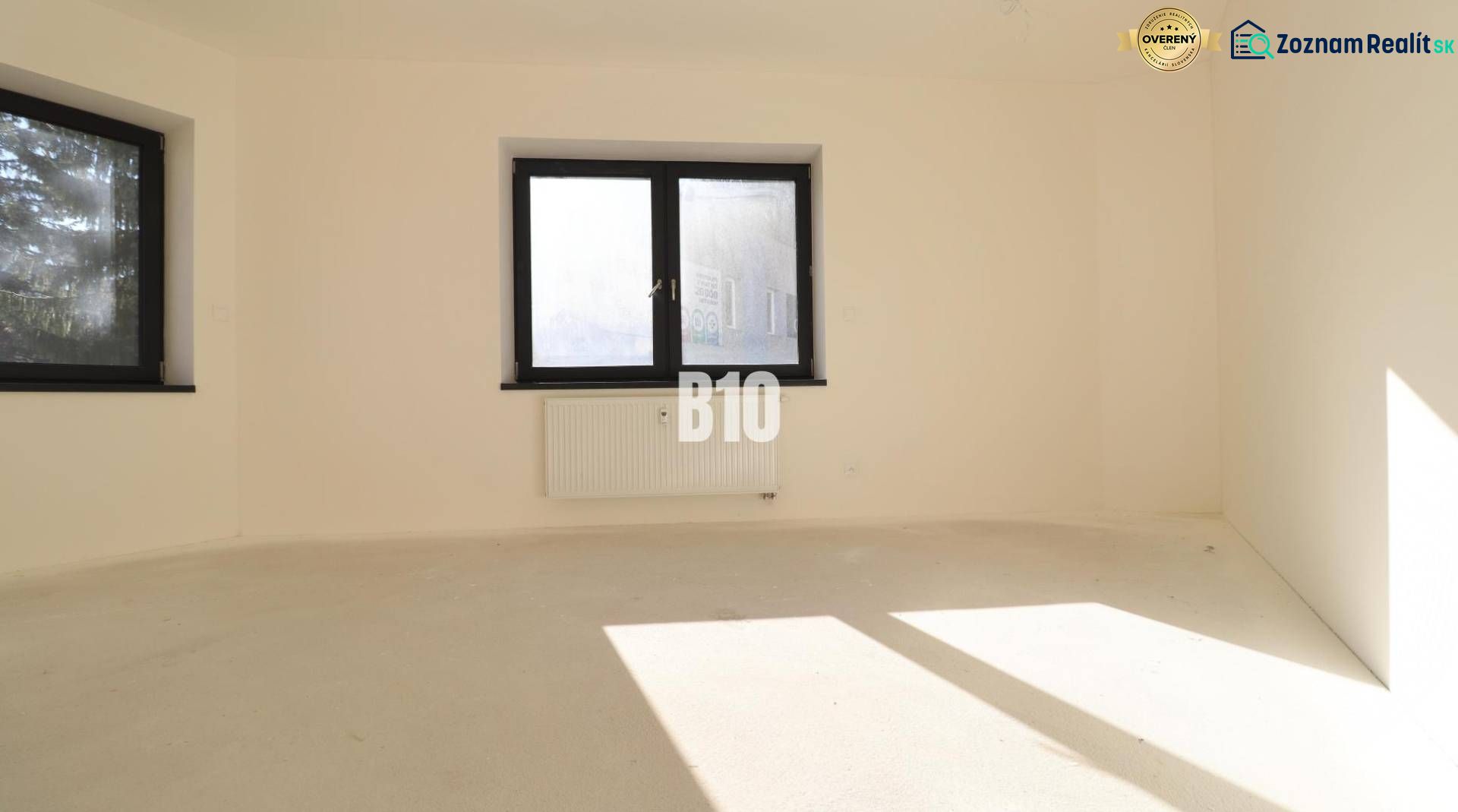 VÝNIMOČNÁ INVESTIČNÁ PRÍLEŽITOSŤ! ADMINISTRATÍVNY PRIESTOR (127,87 m²) - Prázdna kancelária s dvoma oknami a radiátorom, svetlé steny, podlaha bez dekoru dreva.