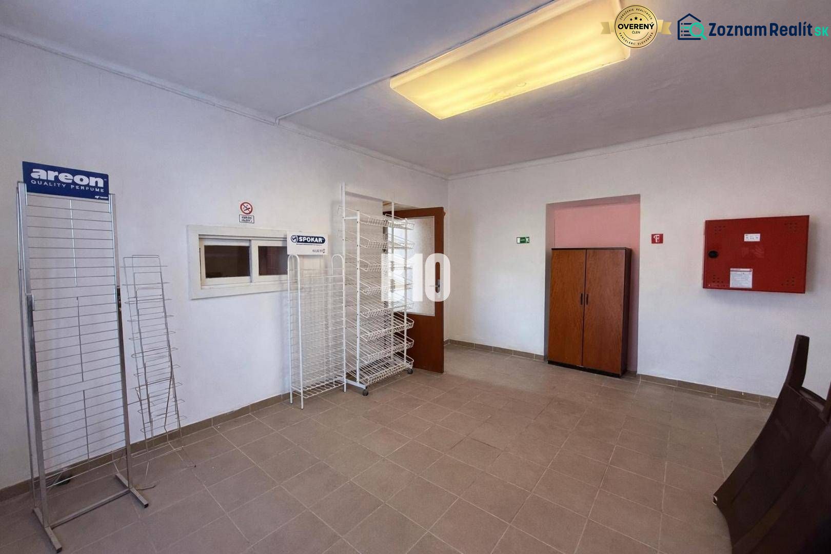 ZREKONŠTRUOVANÁ KOMERČNÁ BUDOVA S VÝBORNOU POLOHOU - Obchodné priestory s prázdnymi regálmi a úložnými skrinkami.