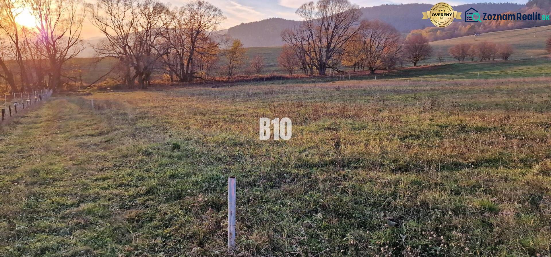 Slnečný pozemok s krásnym výhľadom, 1375m2. - Západ slnka nad zelenými poľami obklopenými stromami a vrchmi, ideálne pre pozemky - bývanie.