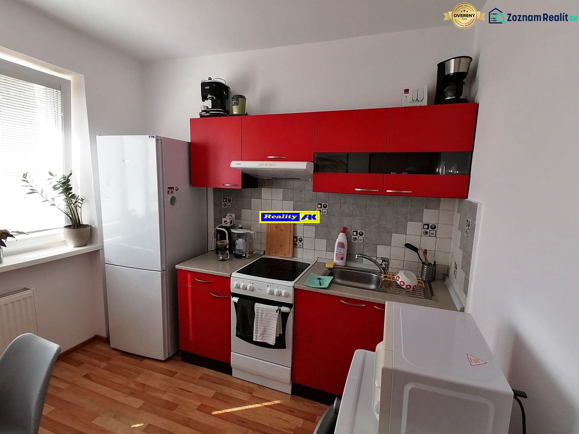 1 izbový byt na predaj rekonštrukcia, Martin centrum, nový balkón - Kuchyňa s červenými skrinkami a podlahou s dreveným dekorom v 1-izbovom byte.