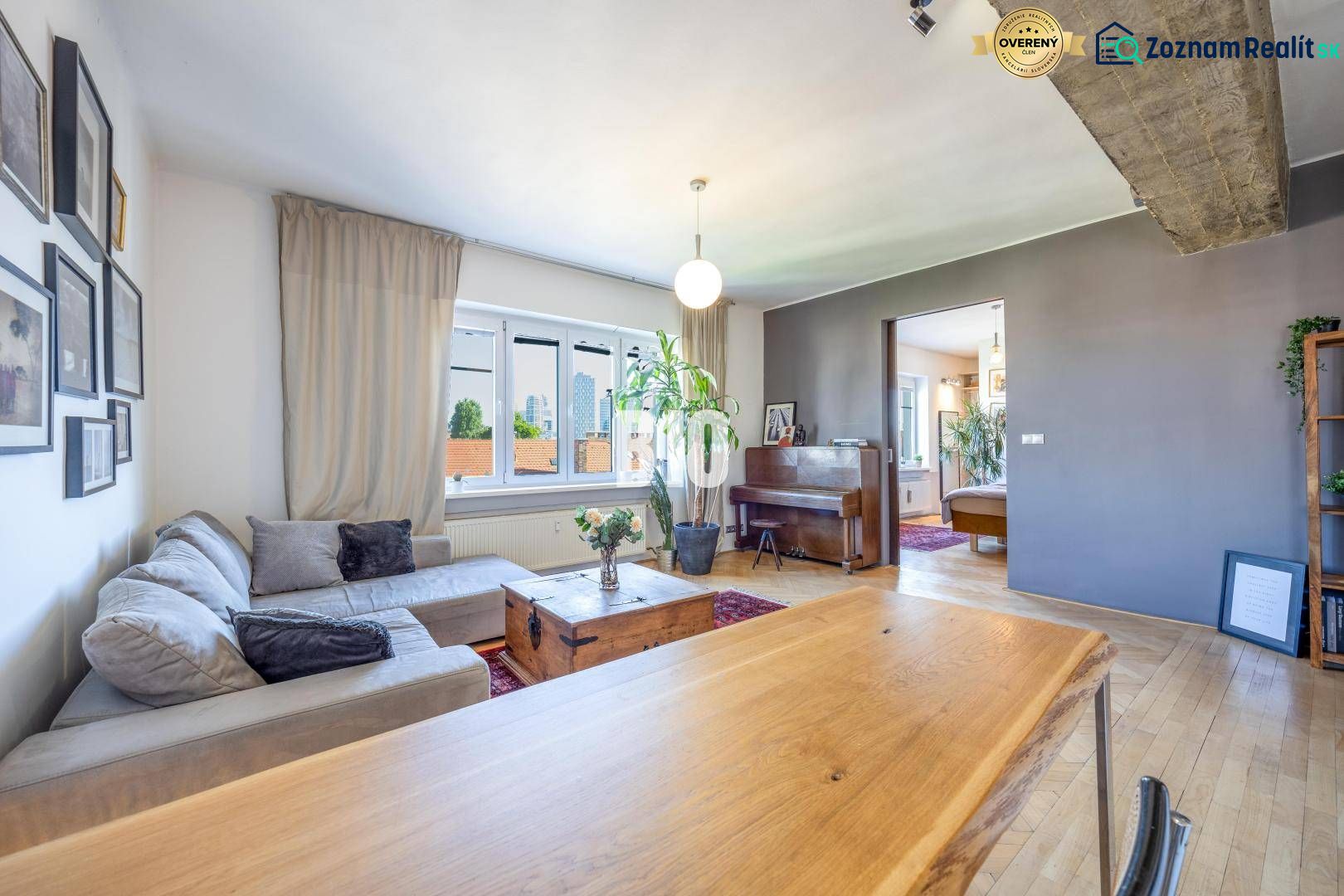 Prenájom | 2-izbový byt | Záhradnícka – Poľská ulica | 900 € + 200 € e - Obývacia izba v 2-izbovom byte s pohovkou, klavírom a podlahou s dreveným dekorom.