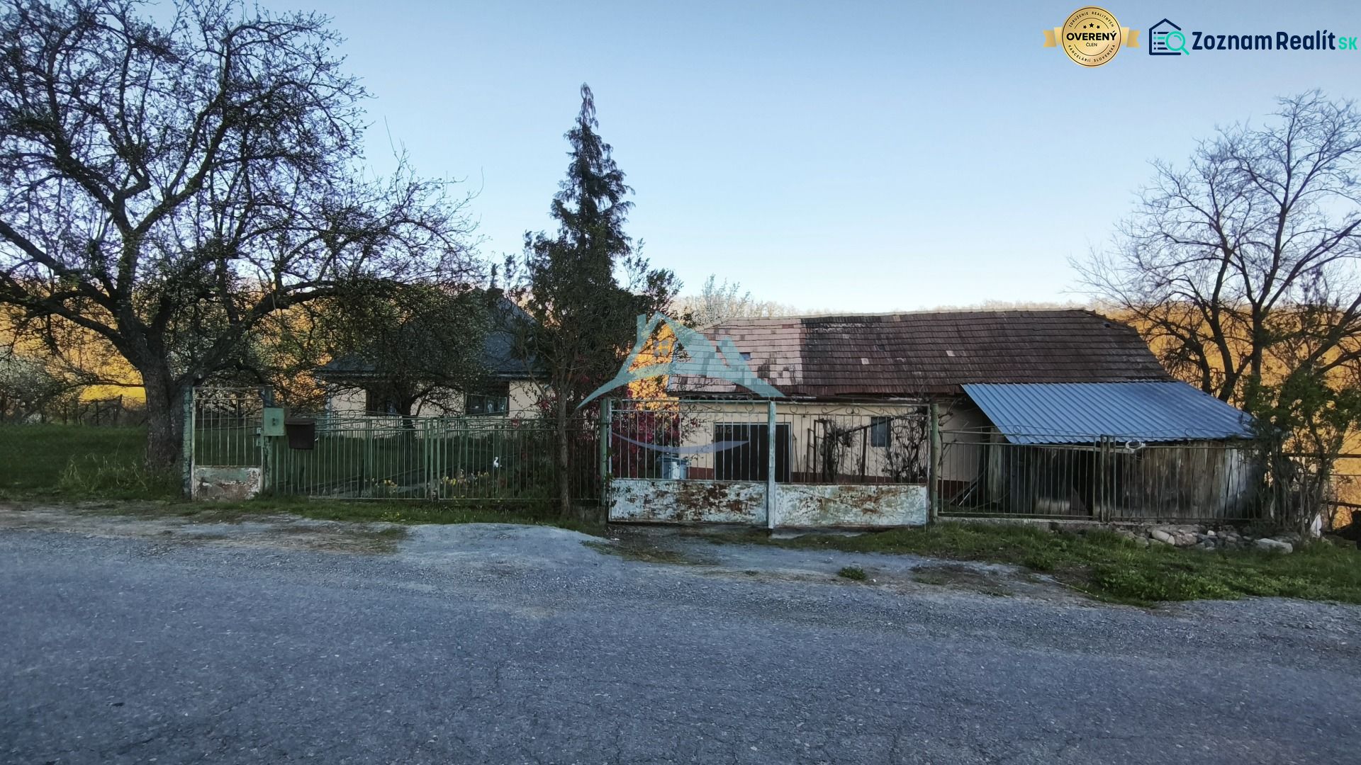 RD (pozemok 9756 m2)  v osade Prieloh, okr. V. Krtíš. - Rodinný dom na ulici Prieloh v Muli so starou strechou a bránou.