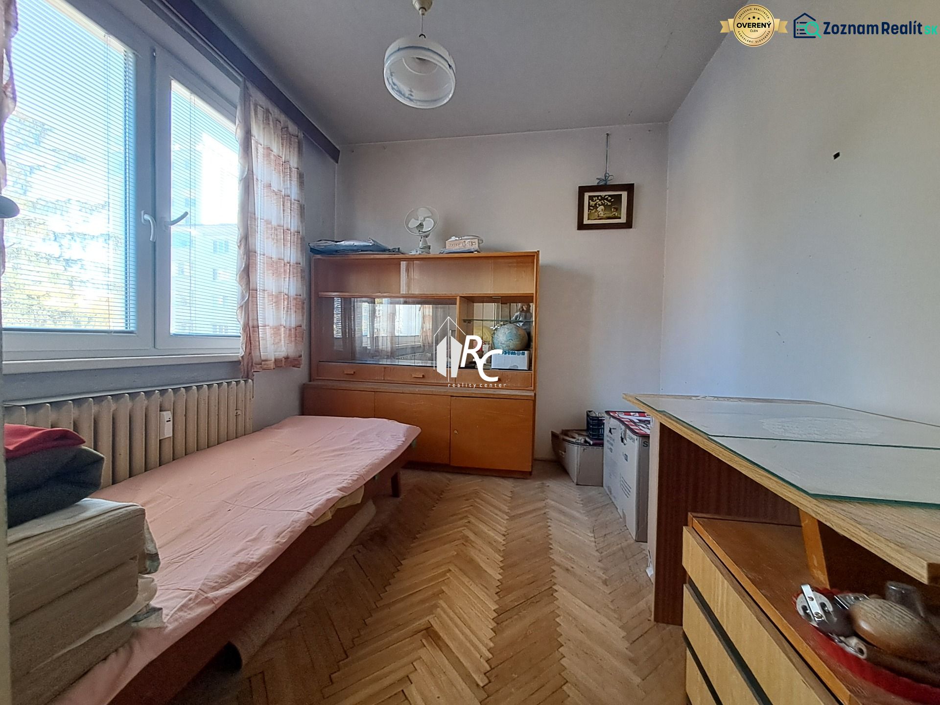 Centrum Martina slnečný 3-izbový byt s balkónom a potenciálom - Malá izba so sedačkou a vitrínou v 3-izbovom byte, podlaha s dreveným dekorom.