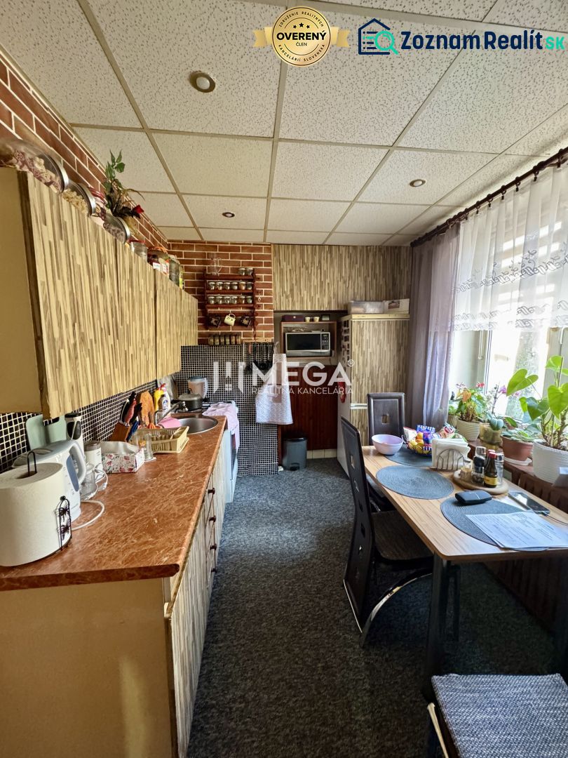 REZERVOVANÉ - Na predaj 2 izbový byt  na Sokolovskej ulici v meste Hum - Kuchyňa v 2-izbovom byte s dreveným dekorom a veľkým oknom, rastliny na parapete.