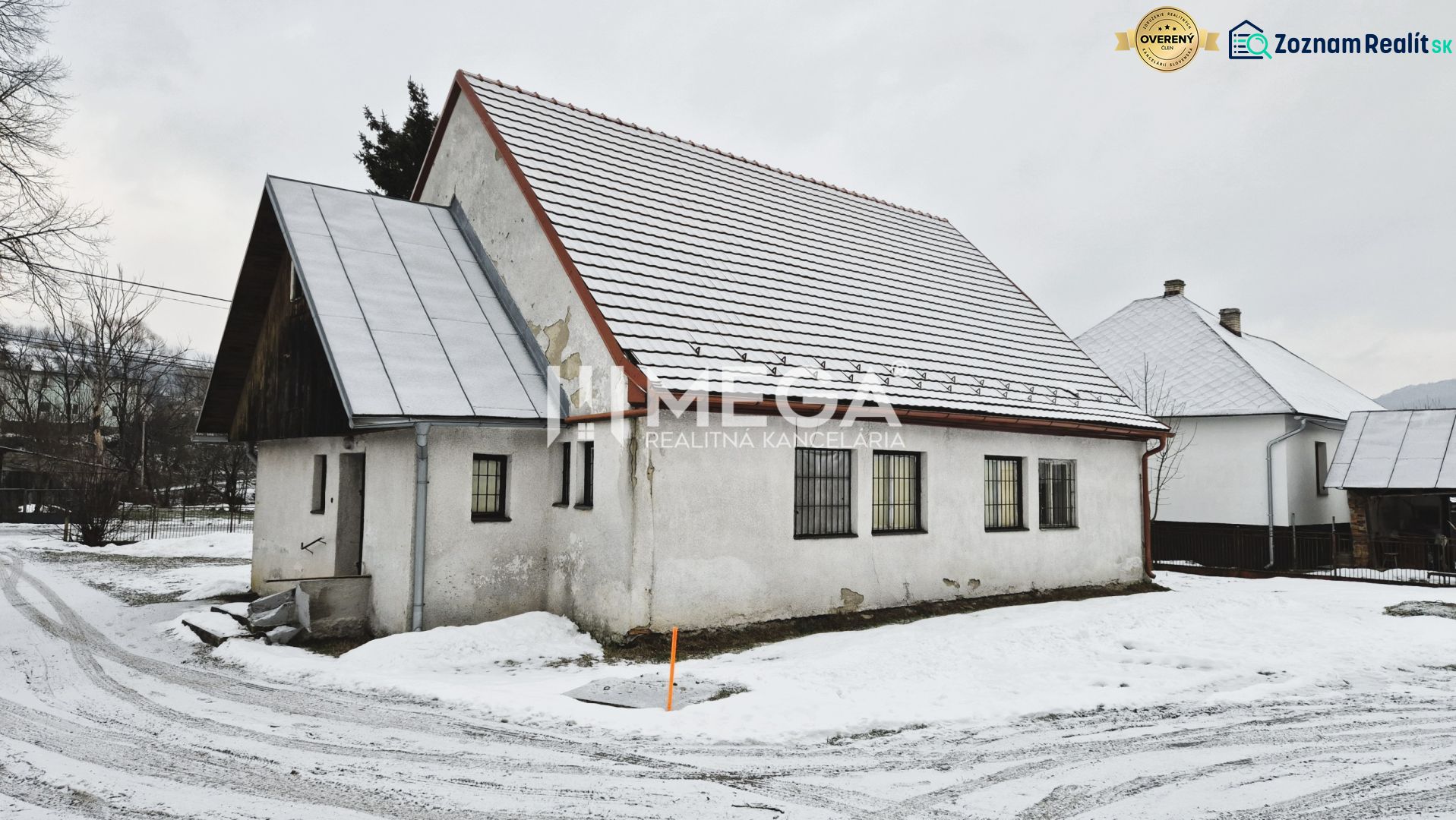 Predaj budovy v obci Zboj - Snehom pokryté obchodné priestory v obci Zboj s tradičnou architektúrou a strechou.