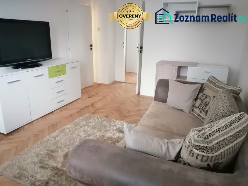 PRENÁJOM: ÚTULNÝ 2 IZBOVÝ BYT S BALKÓNOM, UHLISKO - Obývacia izba v 2-izbovom byte s pohodlnou pohovkou, drevený dekor podlahy a TV.
