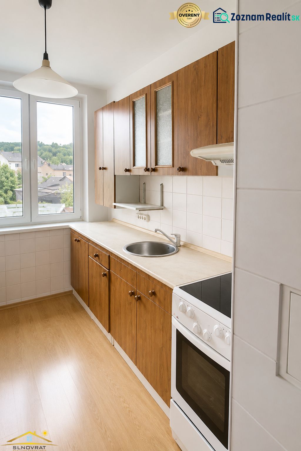 Na predaj: 3-izbový byt v meste Krásno nad Kysucou - Kuchyňa 3-izbového bytu s dverami na balkón a podlahou s dreveným dekorom.