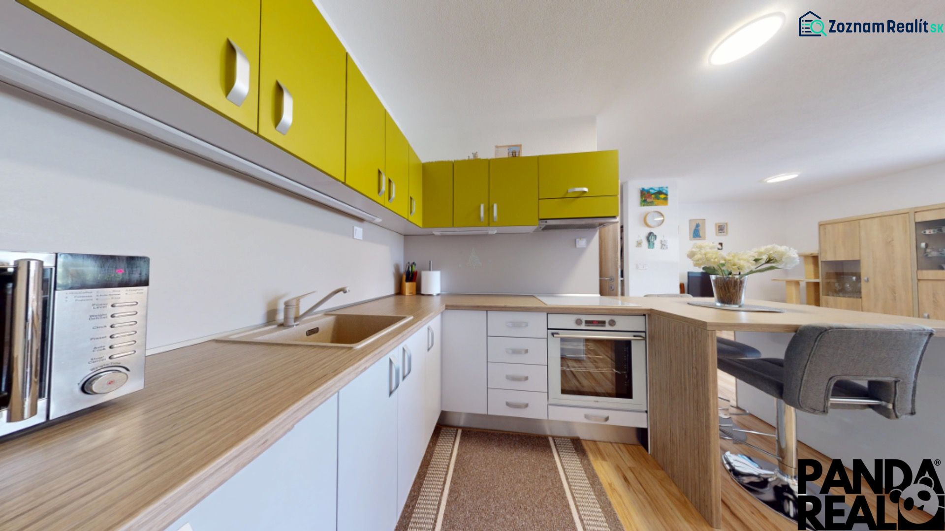 Moderný 3-izbový byt s balkónom a 2 parkovacími miestami - Ludanice - Kuchyňa s farebnými skrinkami a podlahou s dreveným dekorom v 3-izbovom byte.