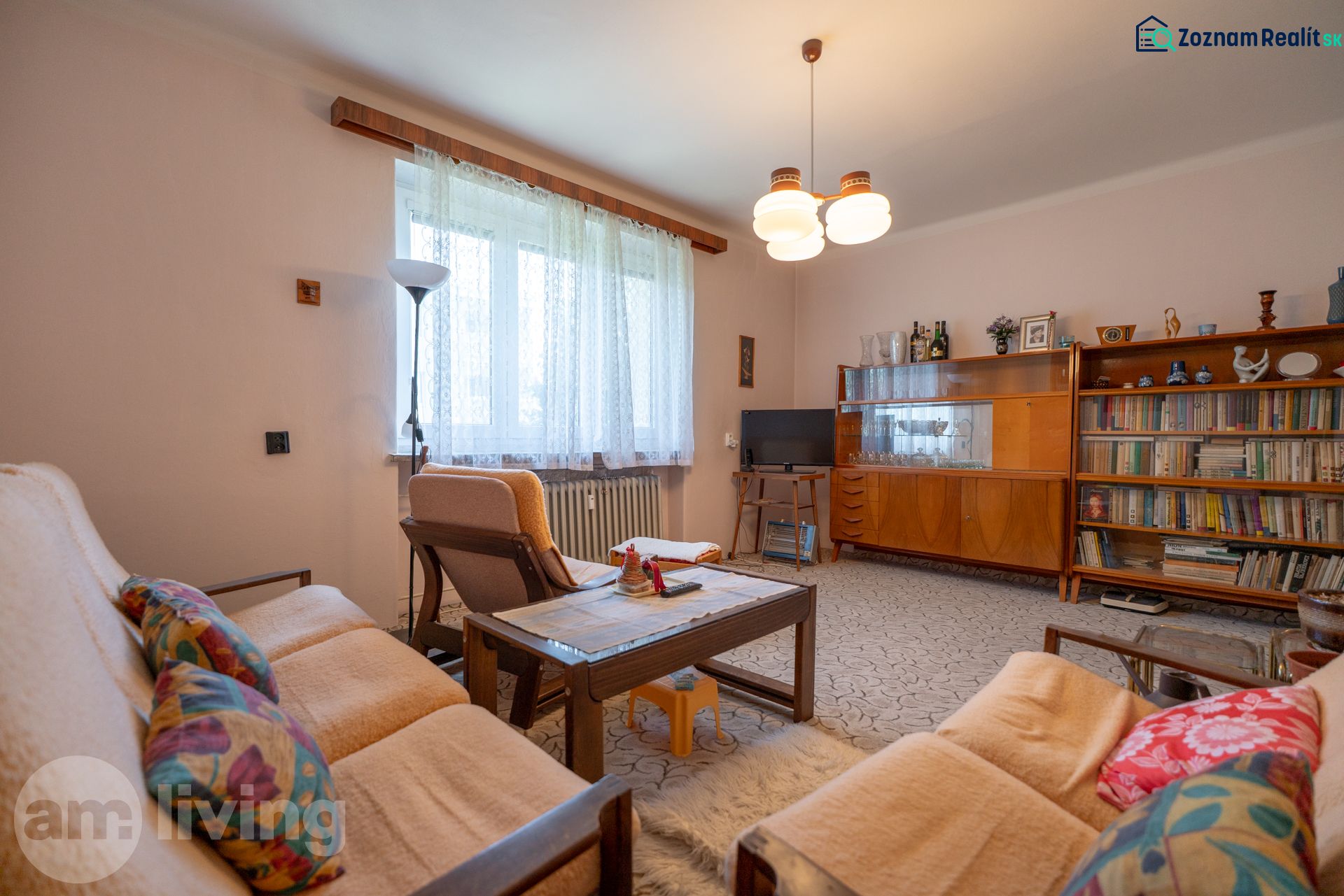 TOP LOKALITA - 3i 67m2 + loggia - Švermova Trenčín - Obývacia izba v 3-izbovom byte s retro nábytkom, pohovkou a knižnicou.