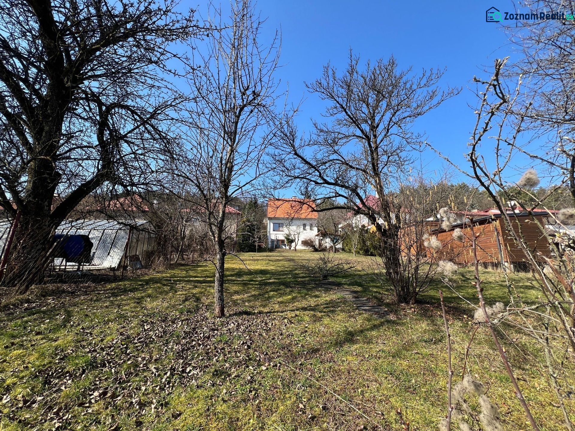 ROVINATÝ POZEMOK  S PRÍSTUPOM Z DVOCH STRÁN+ RODINNÝ DOM – B. Bystrica - Záhrada v okrese Banská Bystrica okolo rodinného domu s trávnikom a stromami.
