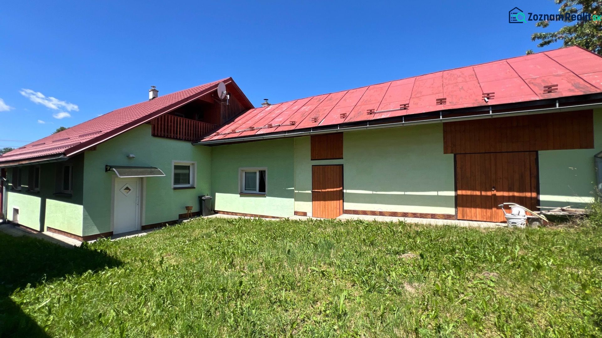 Rodinný dom pre veľkú rodinu s priestorom a súkromím – Polomka - Rodinný dom v Polomke s farebnými fasádami a červenou strechou na pozadí modrej oblohy.