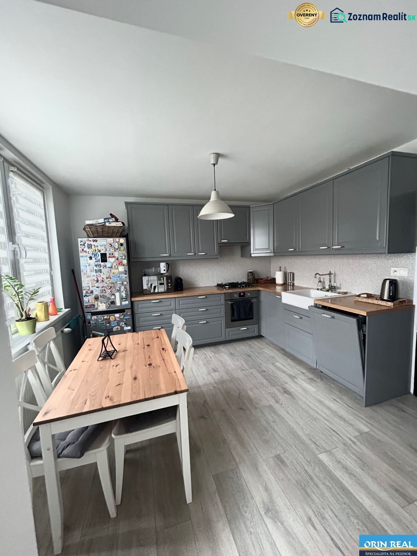 NA PRENÁJOM Pekný 2 izbový byt v Centre Pezinka 700,- EUR - Kuchyňa v 2-izbovom byte s podlahou s dreveným dekorom a šedými skrinkami.