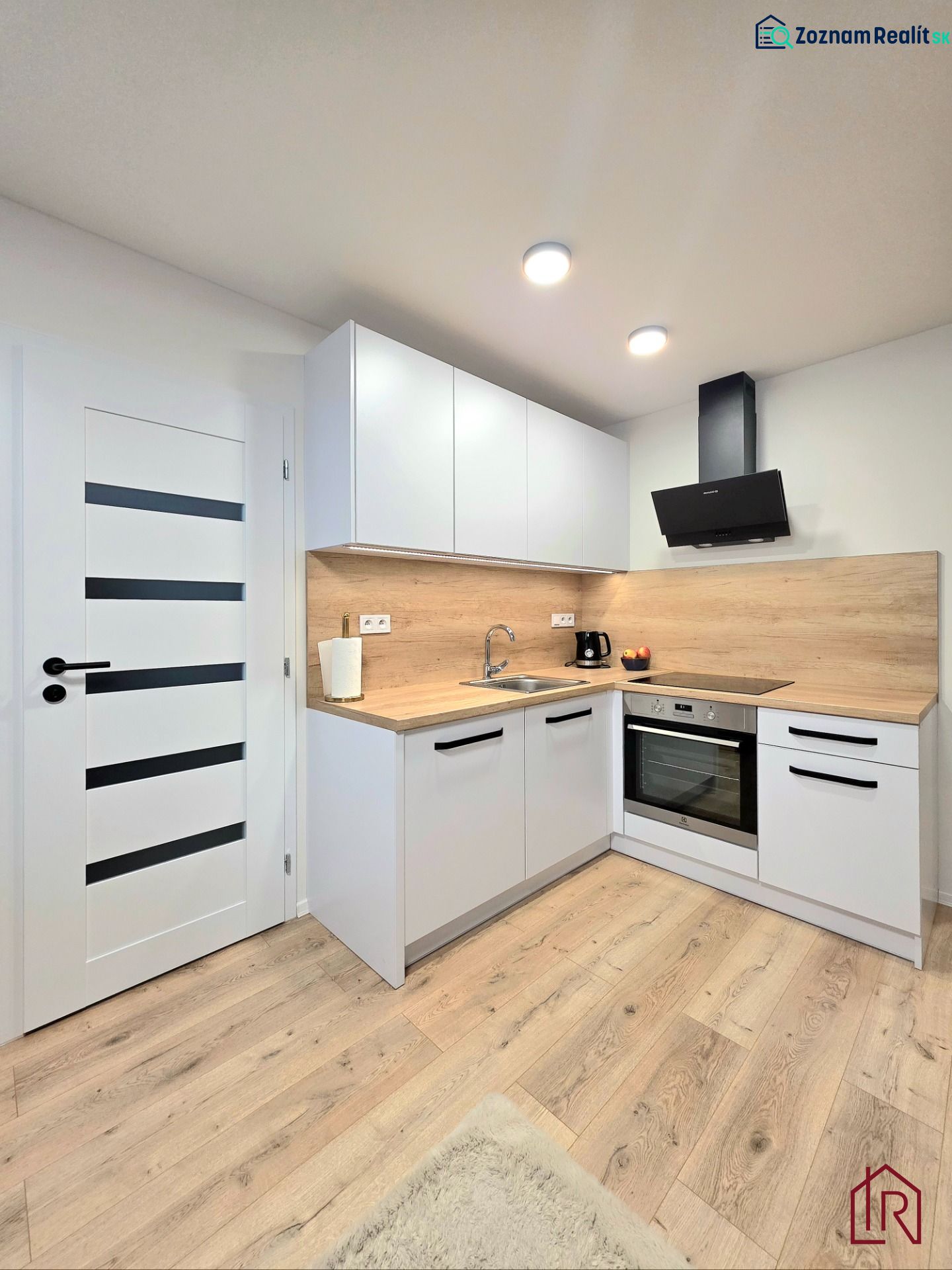 : 1,5-izbový byt, Košice – Juh, loggia, 43 m² - Kuchyňa v 2-izbovom byte s bielymi skrinkami a podlahou s dreveným dekorom.