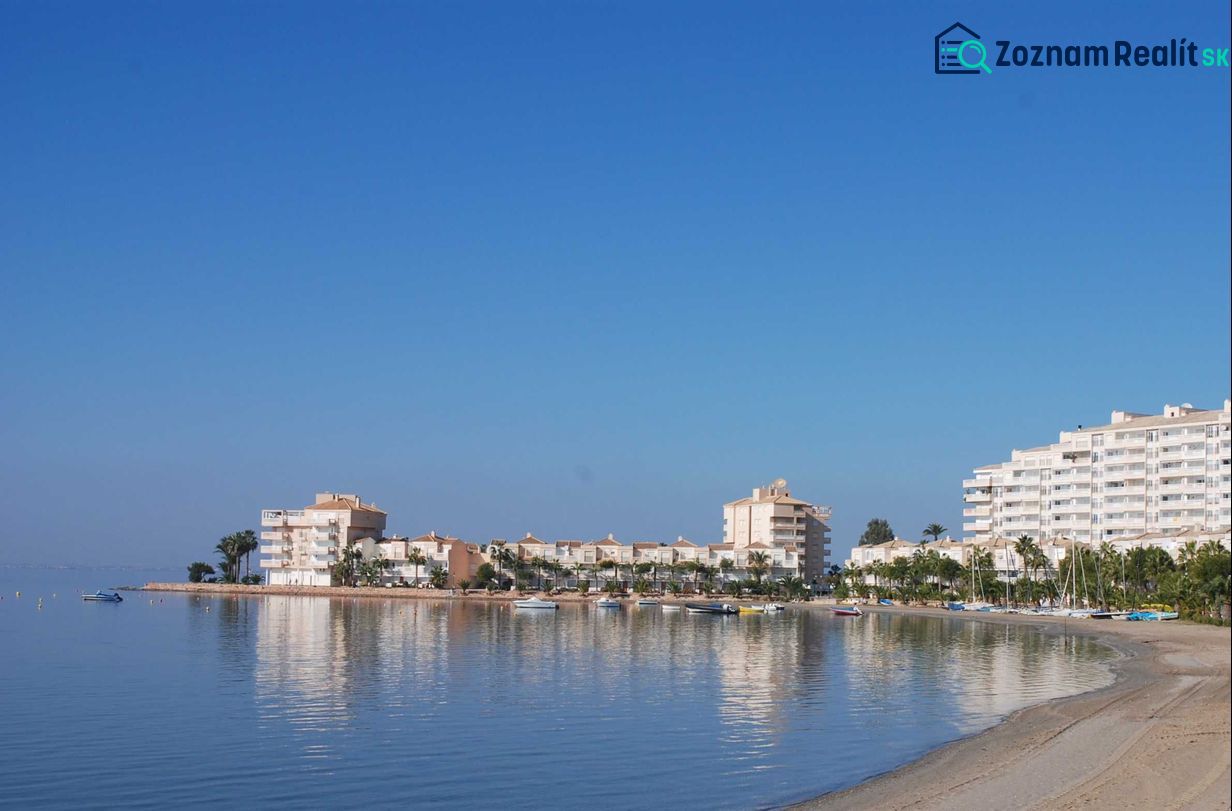 Predaj- Apartmány - La Manga del Mar Menor- Španielsko  - Pobrežie s rekreačnými apartmánmi v La Manga del Mar Menor pri pokojnom mori a modrej oblohe.