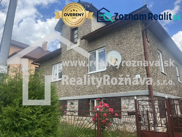 Rodinný dom zo záhradou - Rudná - Rodinný dom v Rudnej s textúrovanou fasádou, zeleným plotom a kvetmi v záhrade.