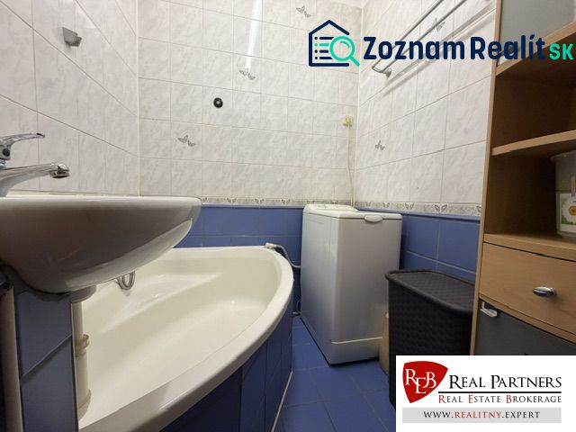 Predaj pekný 1 izbový byt, 35 m2, Dudvážska ulica, BA II. - Kúpeľňa v 1-izbovom byte s vaňou a práčkou, obložená bielymi a modrými dlaždicami.