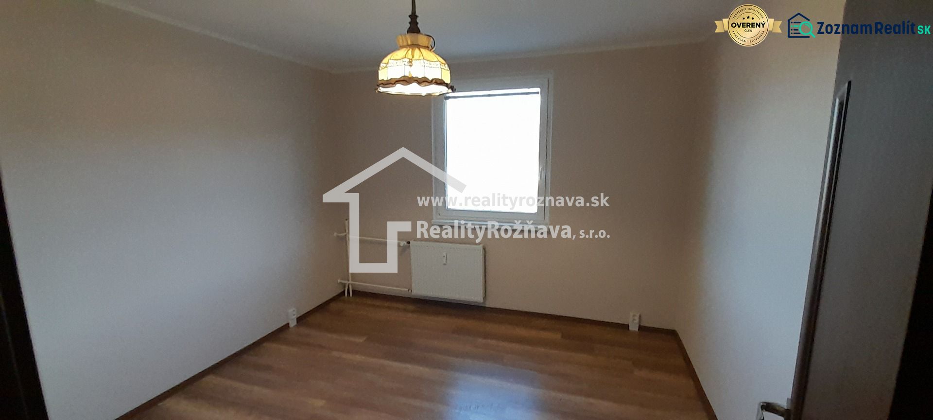 Pekný 2 izbový byt s balkónom na prenájom. - Izba v 2-izbovom byte s podlahou s dreveným dekorom a svetlom nad radiátorom.