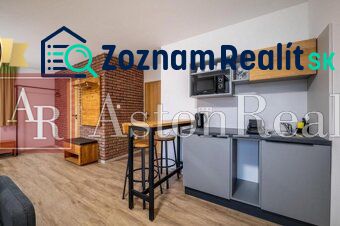 Predaj! Rekreačný apartmán pod Tatrami – Dovalovo - Interiér 1-izbového bytu s podlahou s dreveným dekorom a tehlovou stenou.