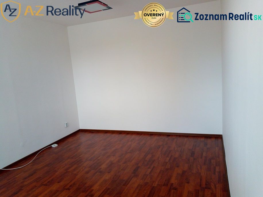 Na prenájom nezariadený 1 izbový byt s balkónom v Nových Zámkoch - Biela stena a podlaha s dreveným dekorom v 1-izbovom byte, základ pre interiér.