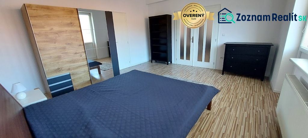 PRENÁJOM: VEĽKOMETRÁŽNY 2 IZBOVÝ BYT S 2 LOGGIAMI, CENTRUM - Spálňa v 2-izbovom byte s posteľou a podlahou s dreveným dekorom.