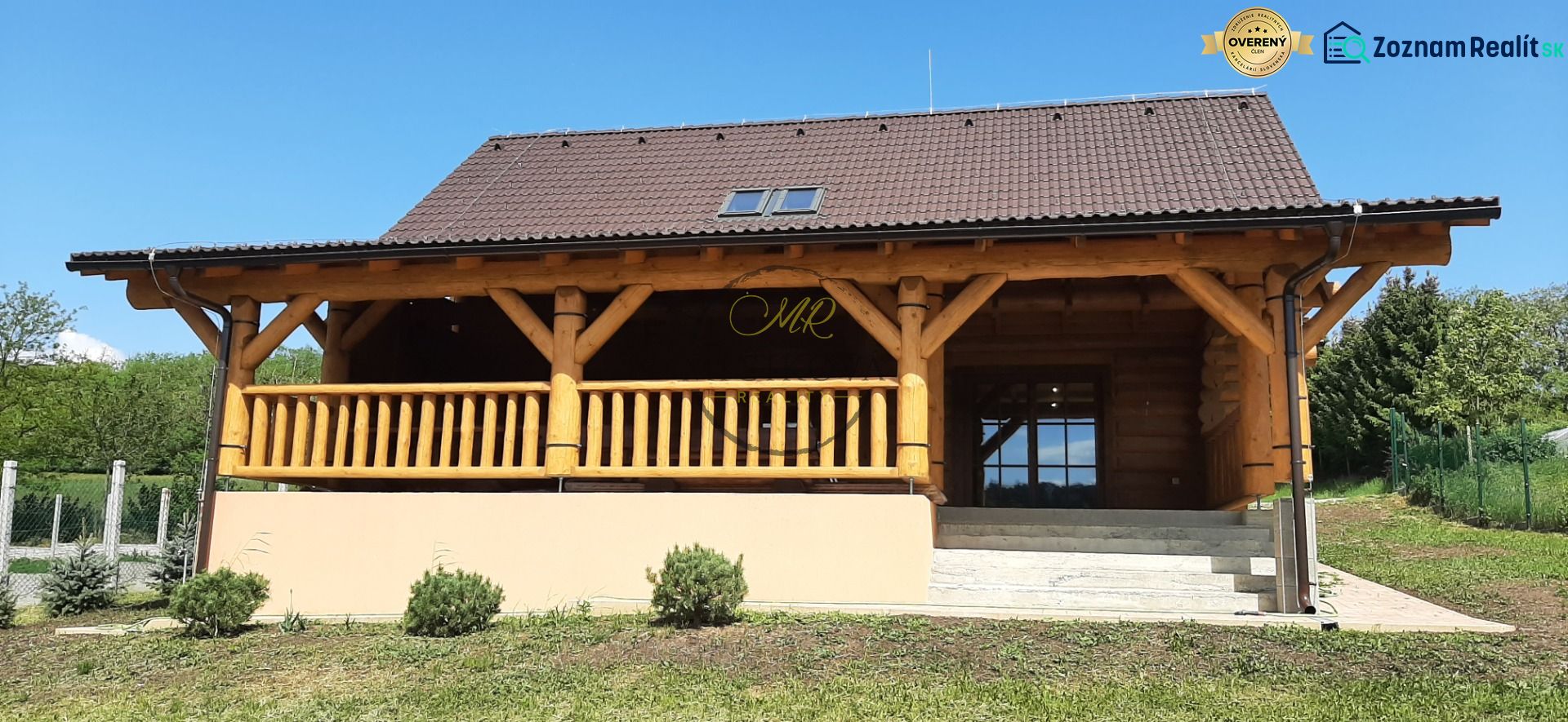 Výnimočná zrubová chata na predaj, Čechy, okr. Nové Zámky - Drevená chata na ulici v Čechách s verandou a zelenou záhradou.