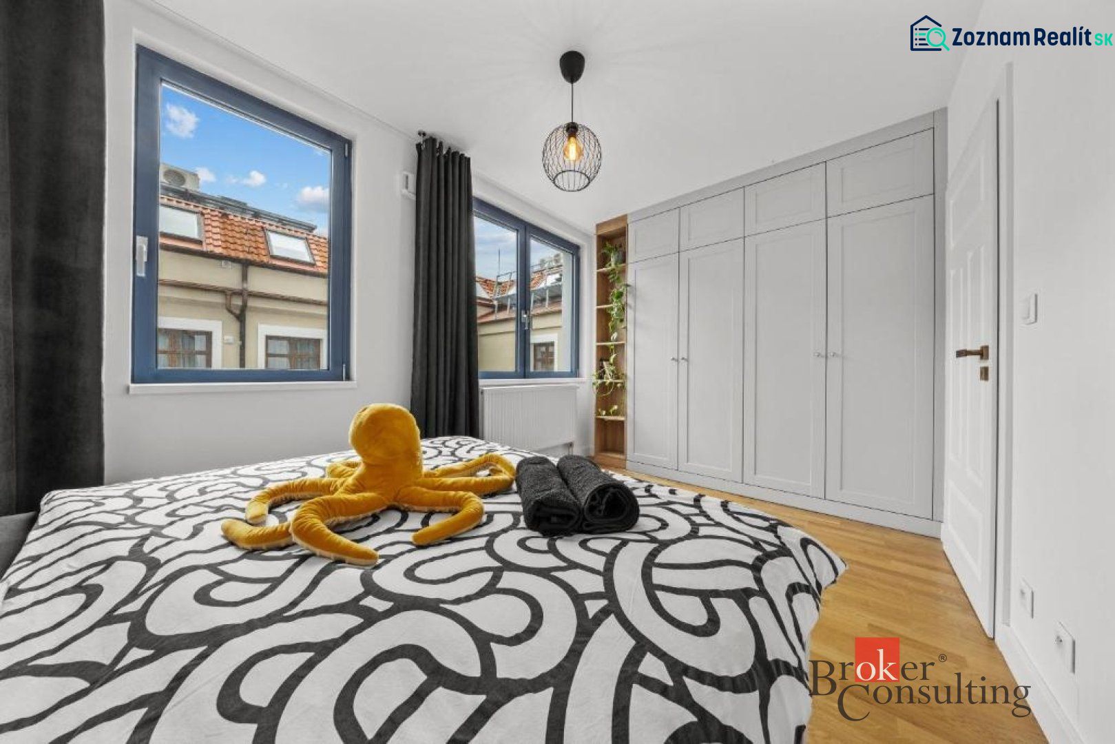 Moderný 2i apartmán v novostavbe v Starom Meste - Spálňa v 2-izbovom byte s veľkými oknami, vstavanou skriňou a podlahou s dreveným dekorom.
