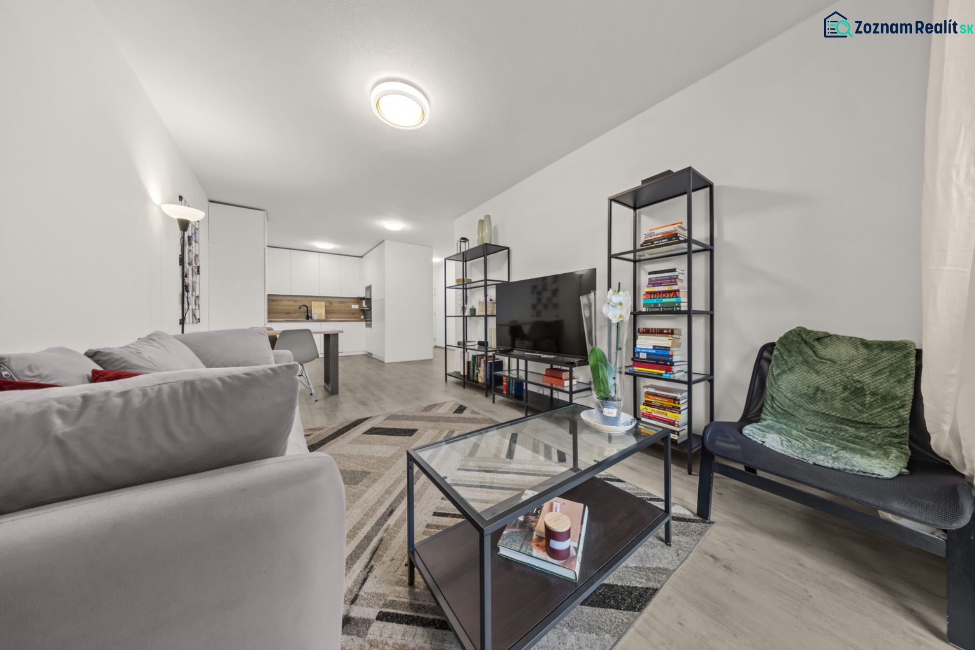 NA PREDAJ: 3-izbový apartmán, MATADORKA, Bratislava - Petržalka - Obývacia izba v 3-izbovom byte s gaučom, policami, sklom a podlahou s dreveným dekorom.