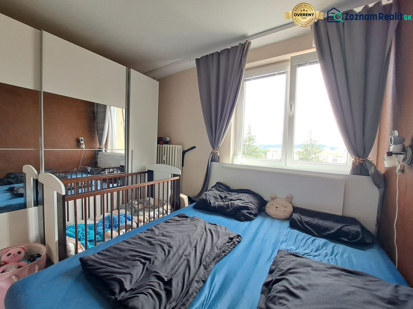Priestranný 3-izbový byt s dvoma balkónmi na prenájom - Spálňa v 3-izbovom byte s posteľou, detskou postieľkou a veľkou skriňou.