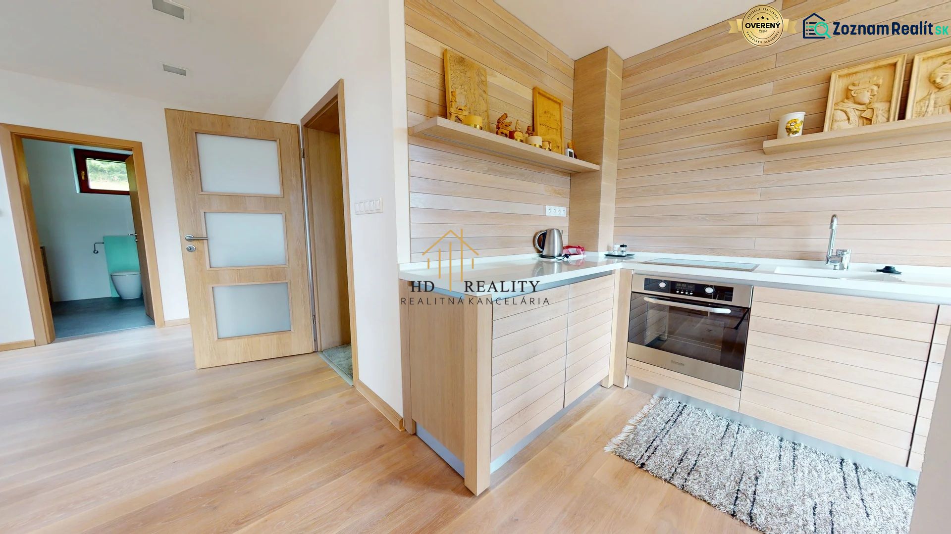 Pripravujeme do ponuky jedinečný apartmánový bytový dom Donovaly  - Interiér chaty s kuchyňou, dreveným dekorom a vstupom do kúpeľne.
